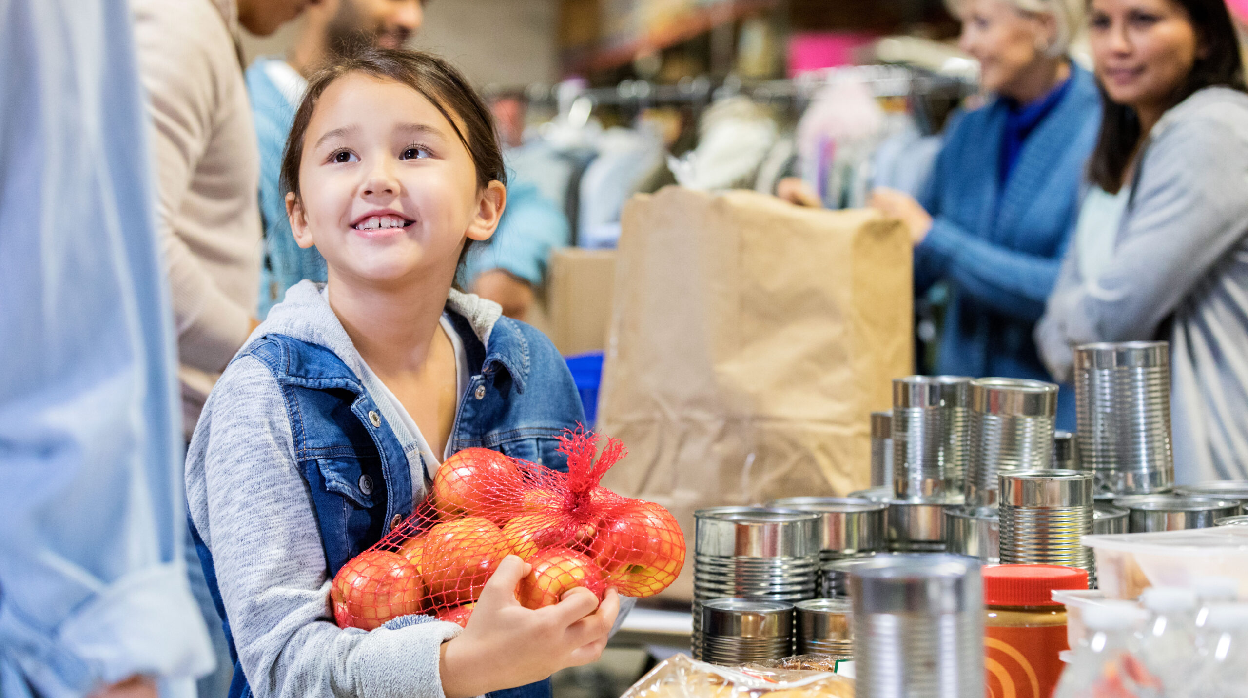 Smiling little girl donates apples to food bank