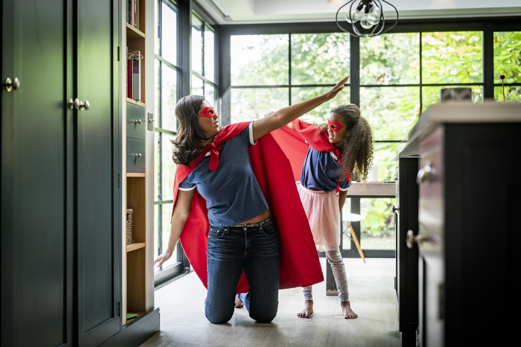 Girl with mother in red superhero costume at home