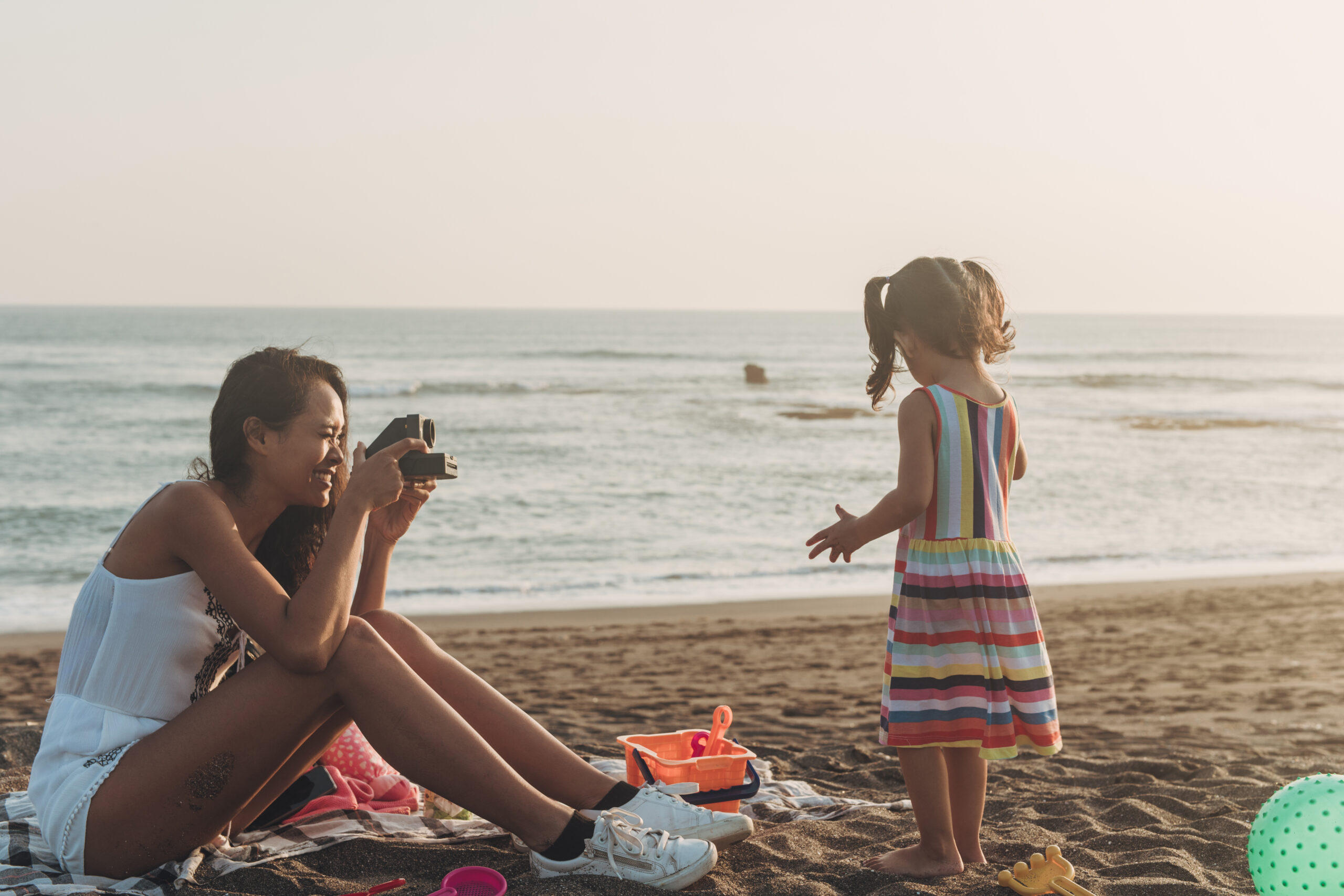 Mother photographing daughter at the beach with instant camera