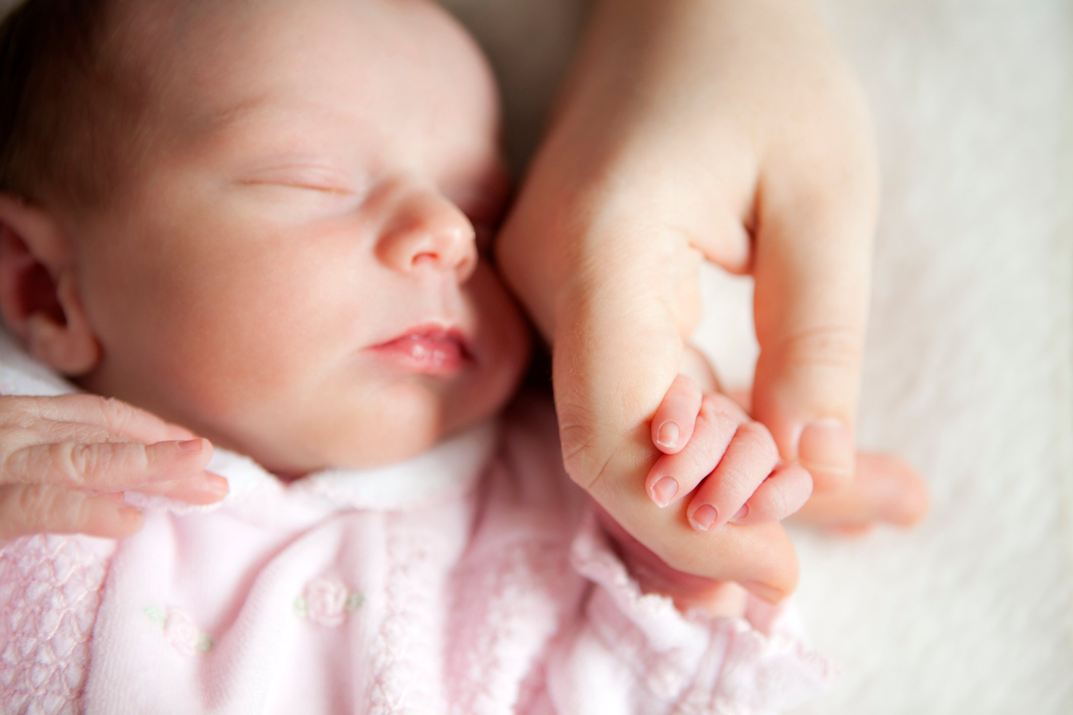 Newborn baby holding mother's hand