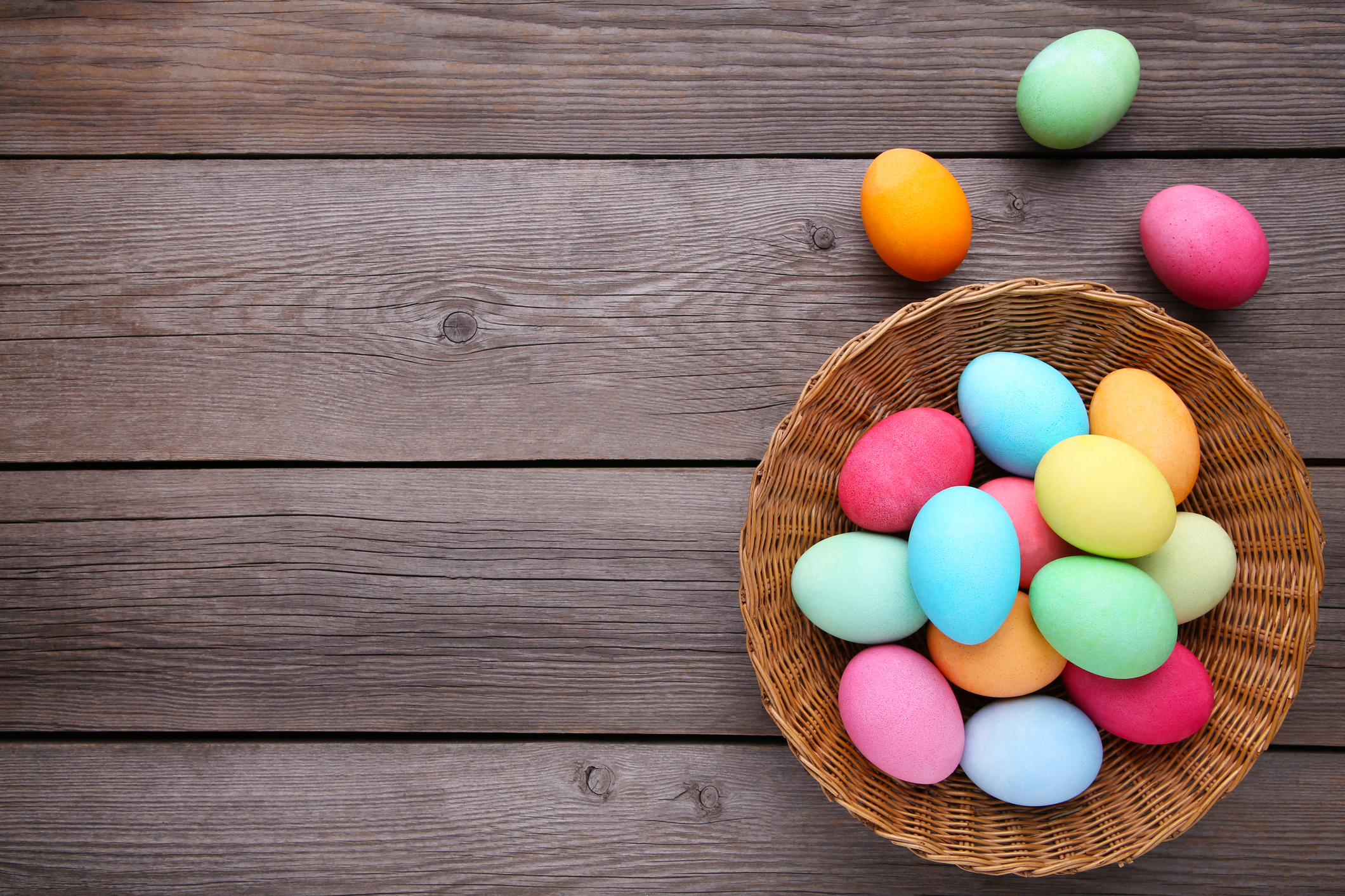 Colorful easter eggs in basket on grey wooden background