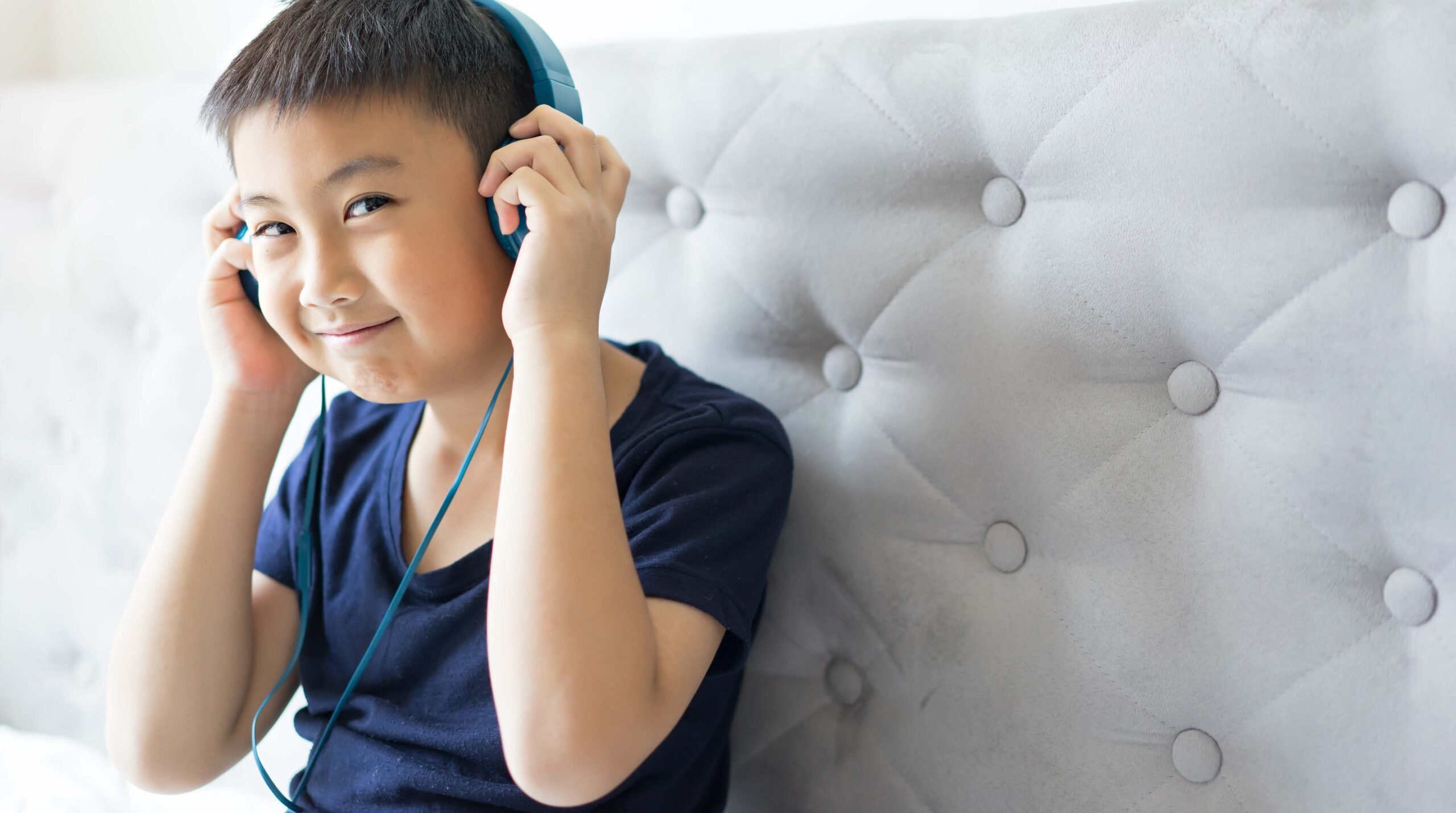 Happy Little boy listening to music on bed at bedroom for relax