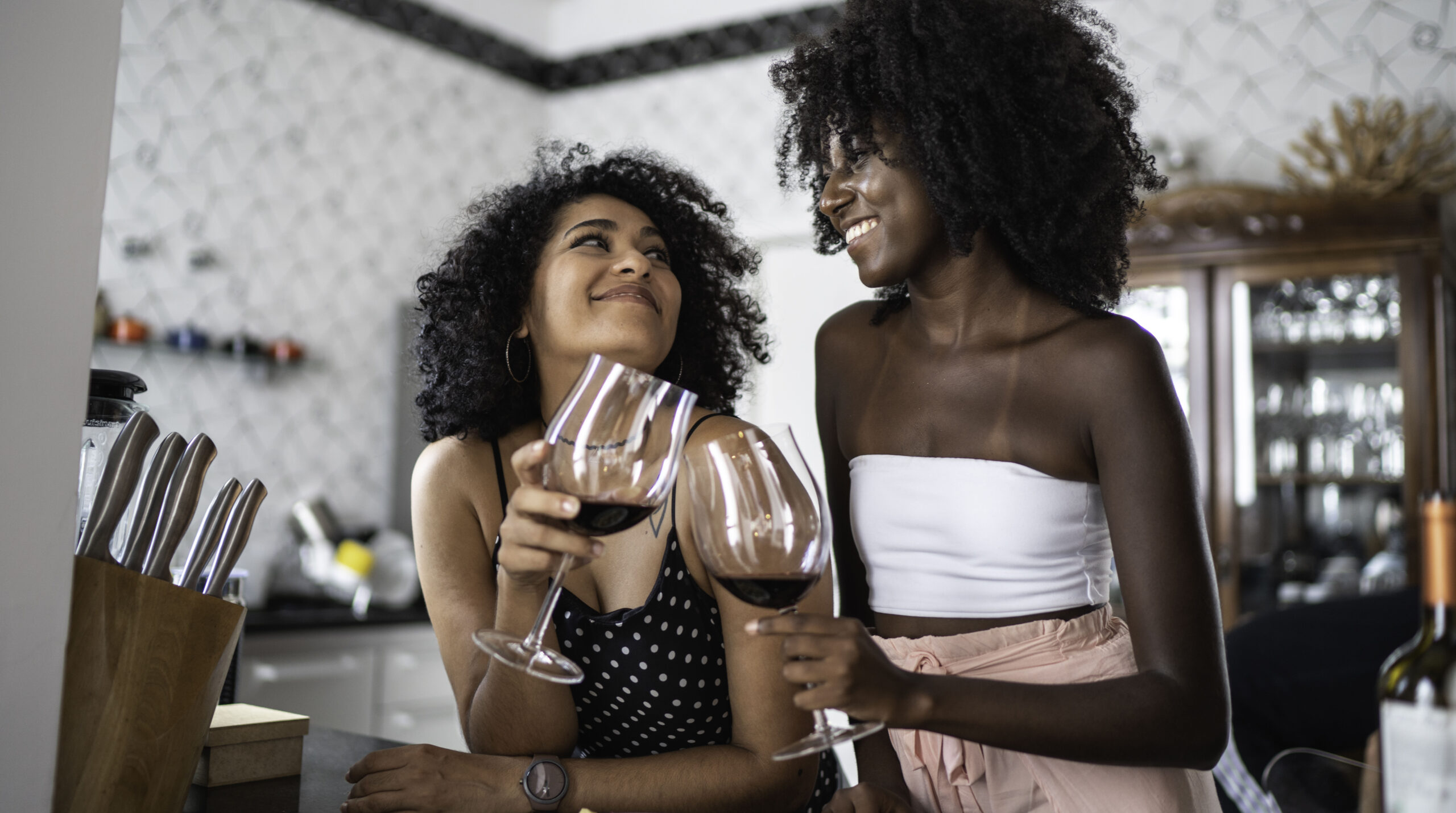 Lesbian Couple or Friends Drinking Wine at Kitchen