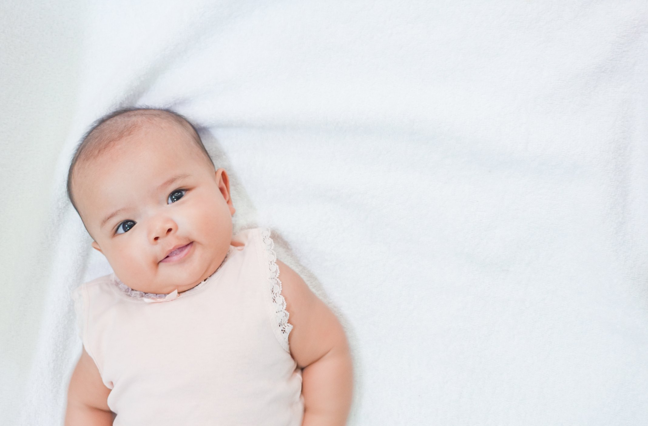 Asian newborn baby gives a sweet smile on white background.
