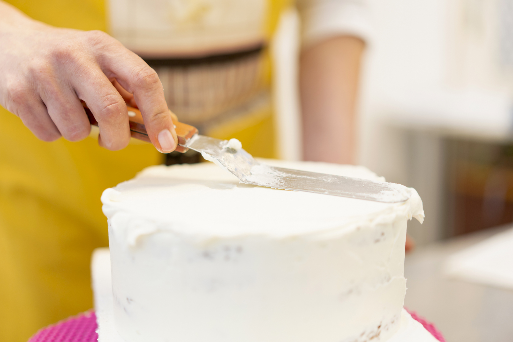 Close up of woman putting icing on the top of a cake