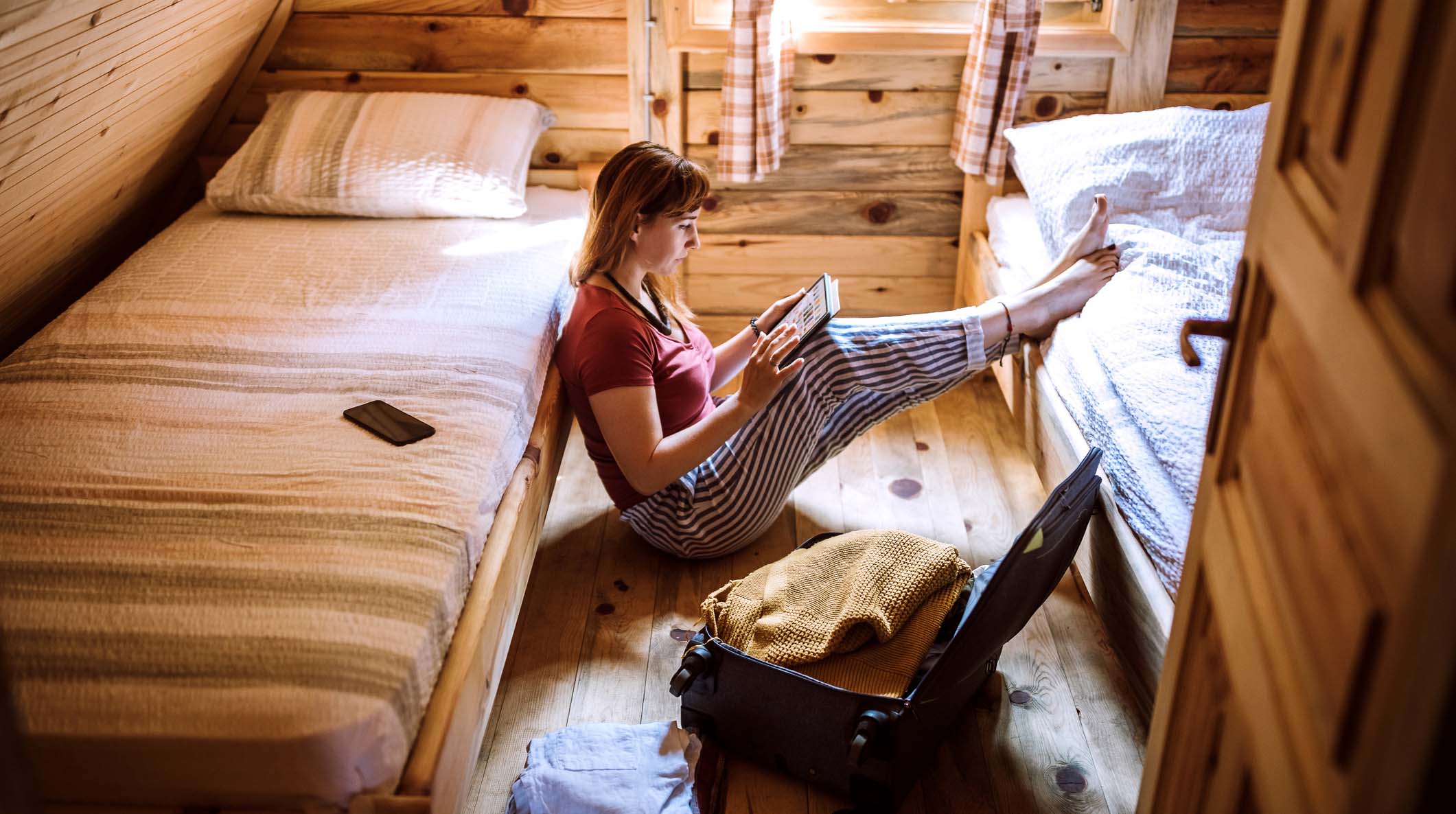 Woman sitting in log cabin and using digital tablet