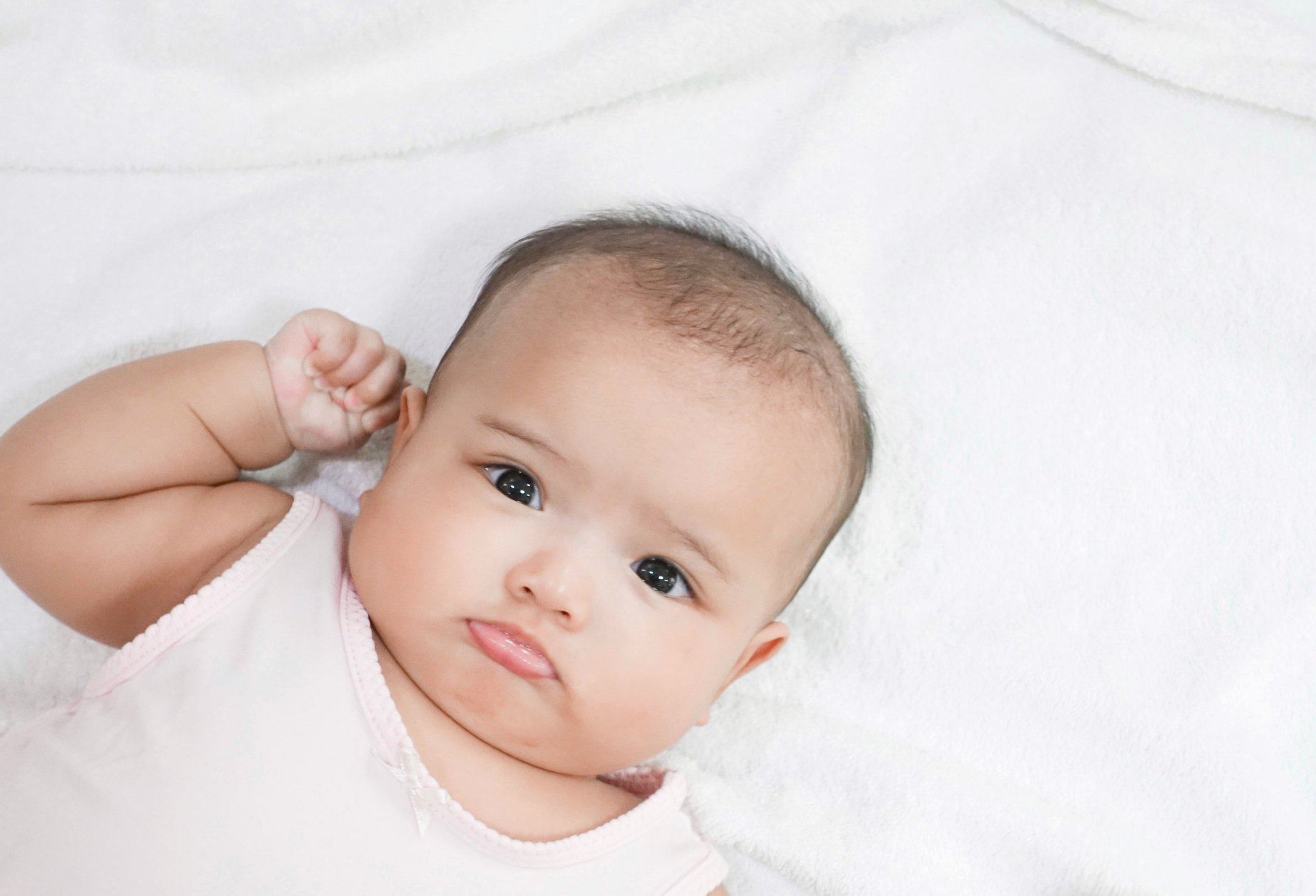 Asian newborn baby girl lying down on white bed