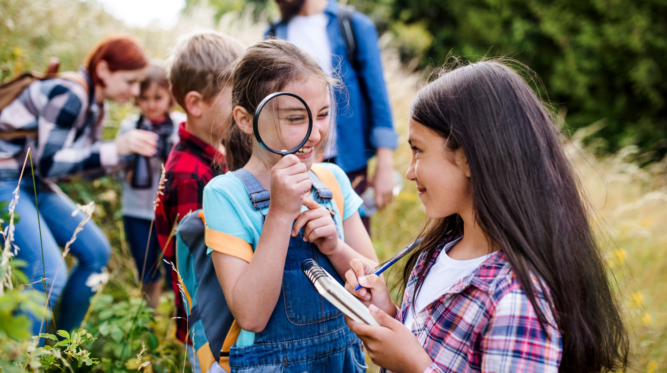 Group of school children with teacher on field trip in nature, learning science.