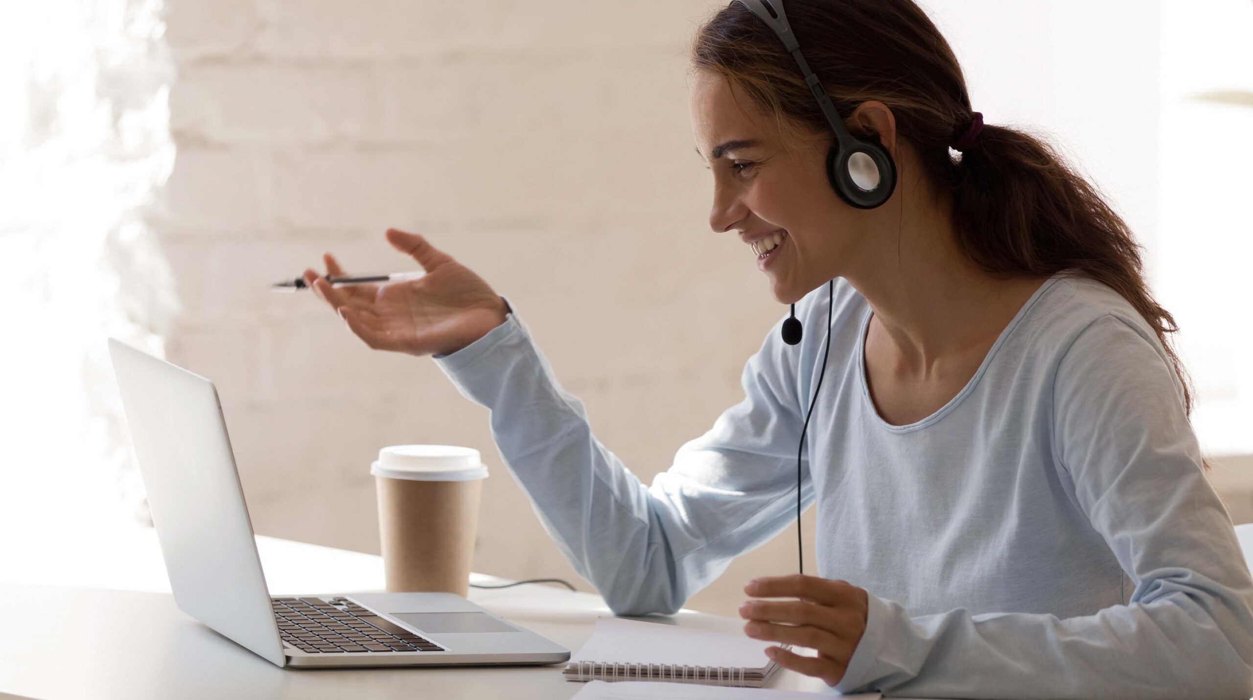 Smiling millennial lady freelancer wearing headset, communicating with client.