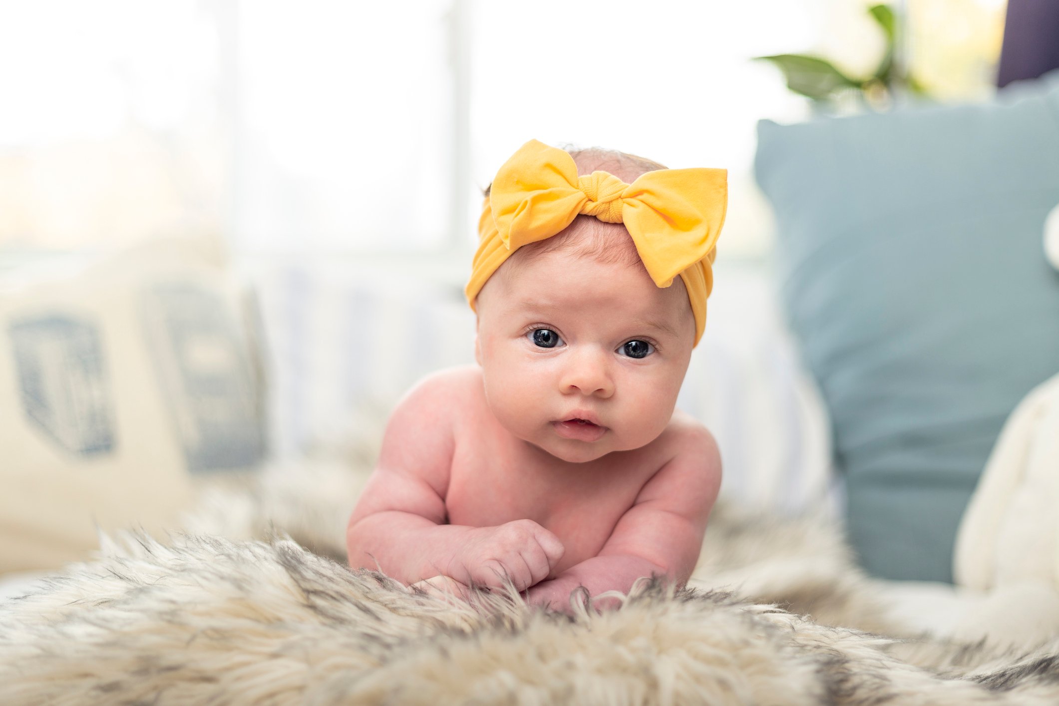 Newborn baby girl posing with a twinkle in her eyes.