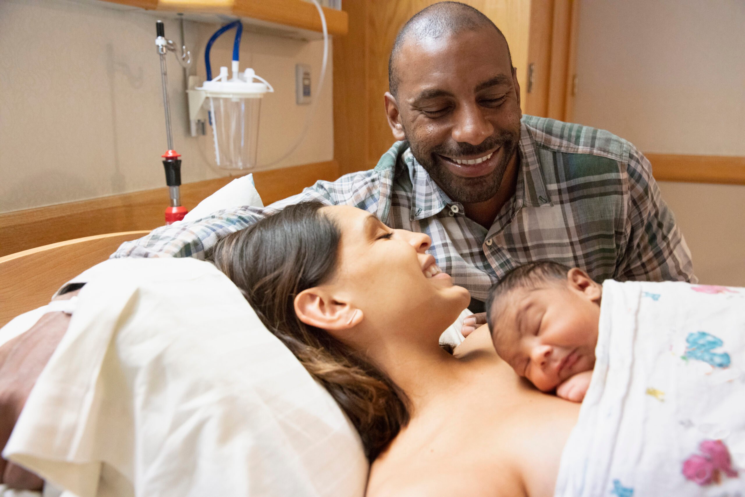 Mixed race family admiring their newborn baby at hospital with mother