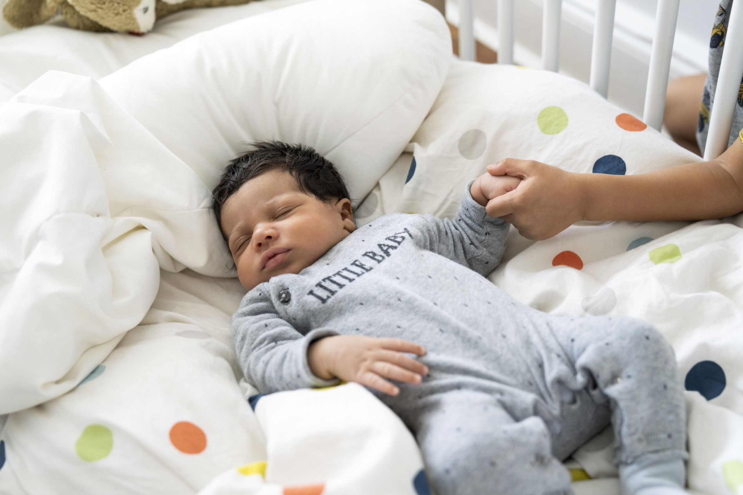 Boy holding hand of brother sleeping in crib