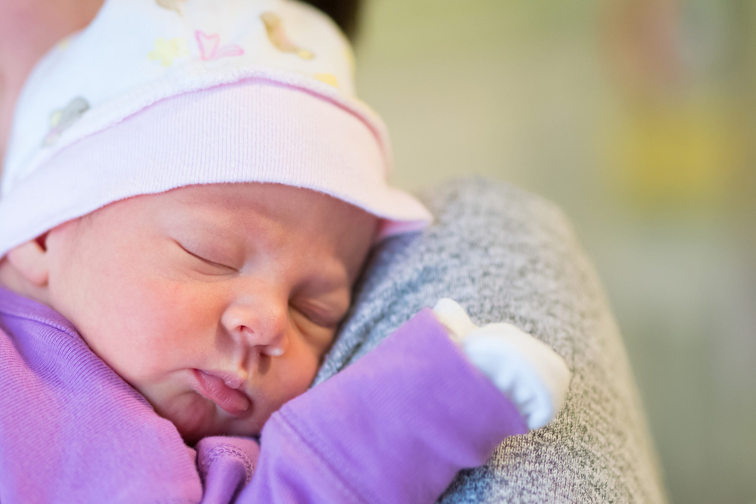 Mom holds her one month old baby girl on the shoulder while she is sleeping.