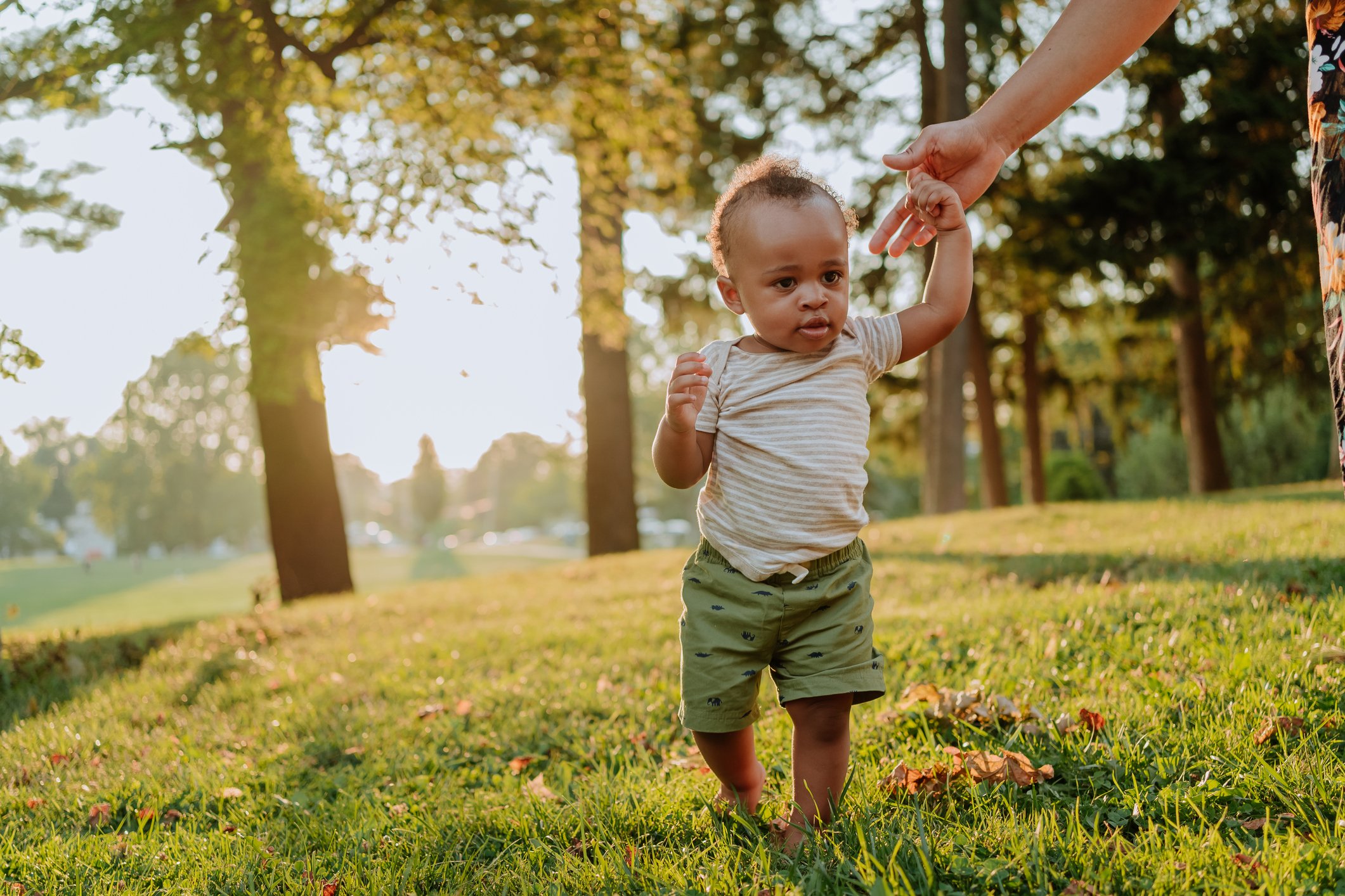 Black child learning to walk and his mother supporting him