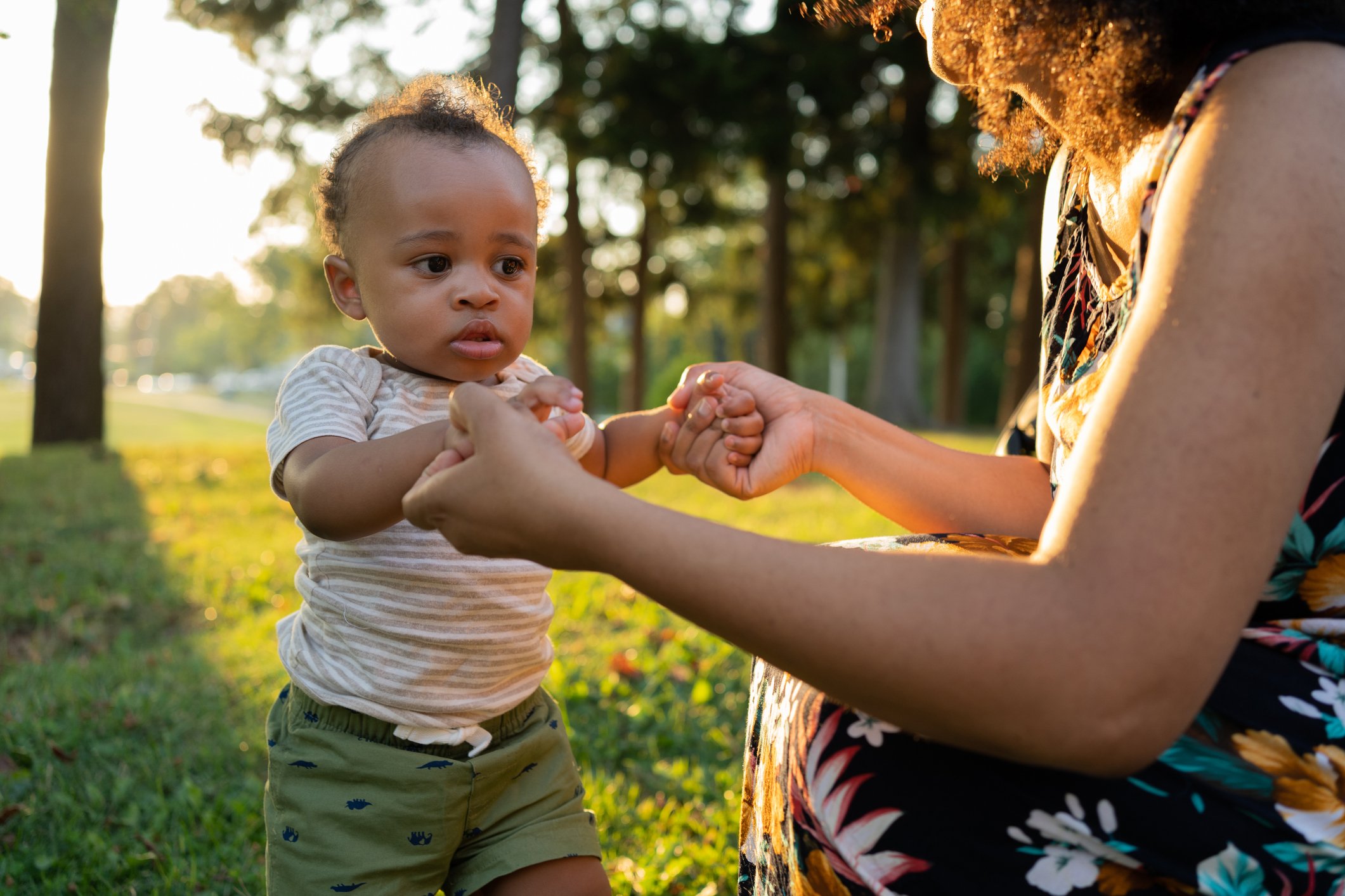 Black child learning to walk and his mother supporting him