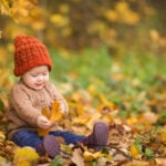 Baby playing with autumn leaves in a forest