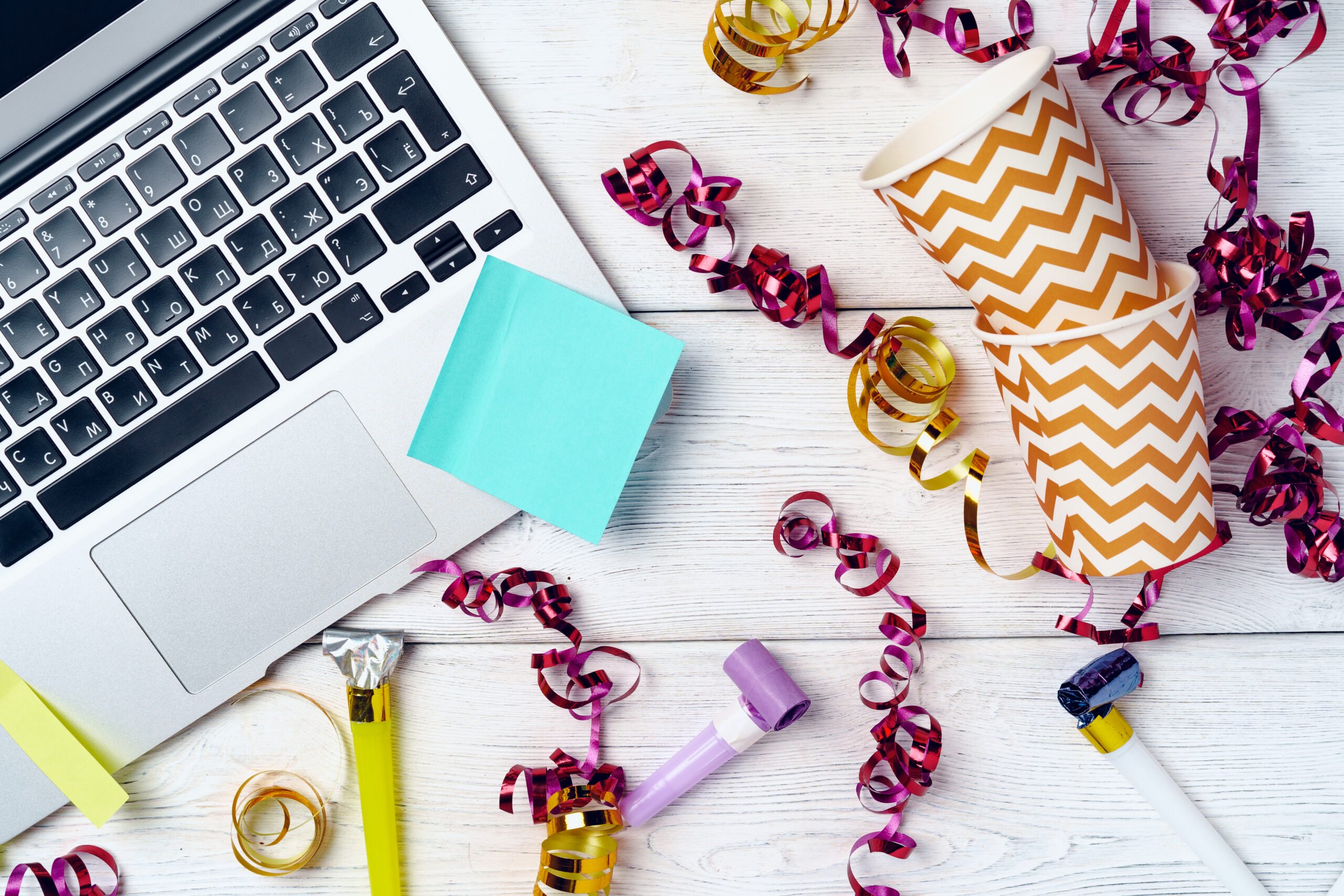Office desk with laptop and open notepad decorated with party streamers