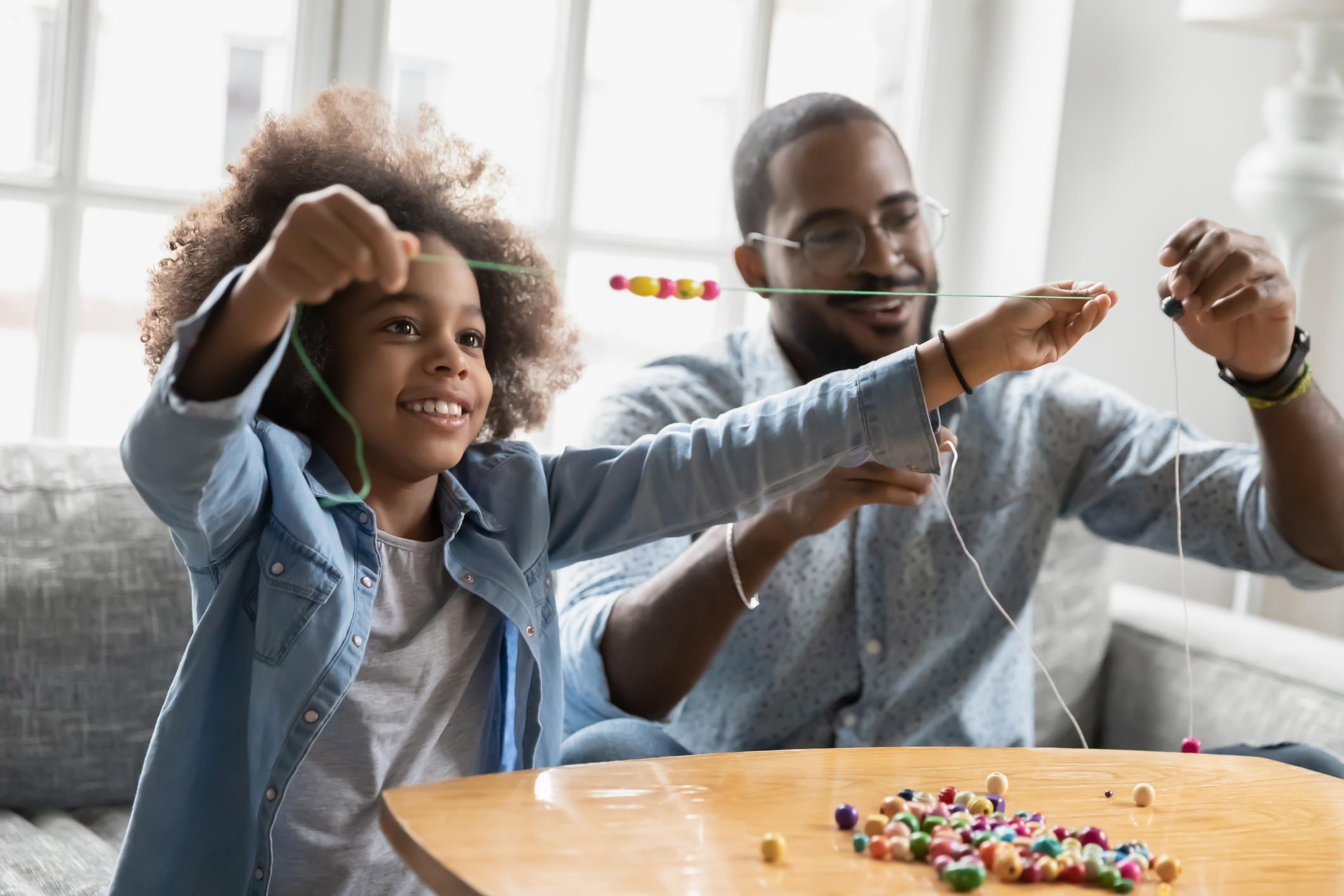 Happy biracial kid girl involved in handmade activity with father.