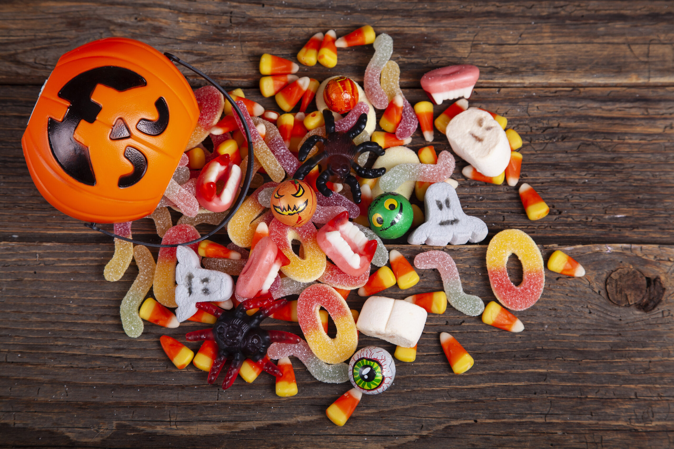 Halloween Jack o Lantern pail with bottom border of spilling candy over brown wood