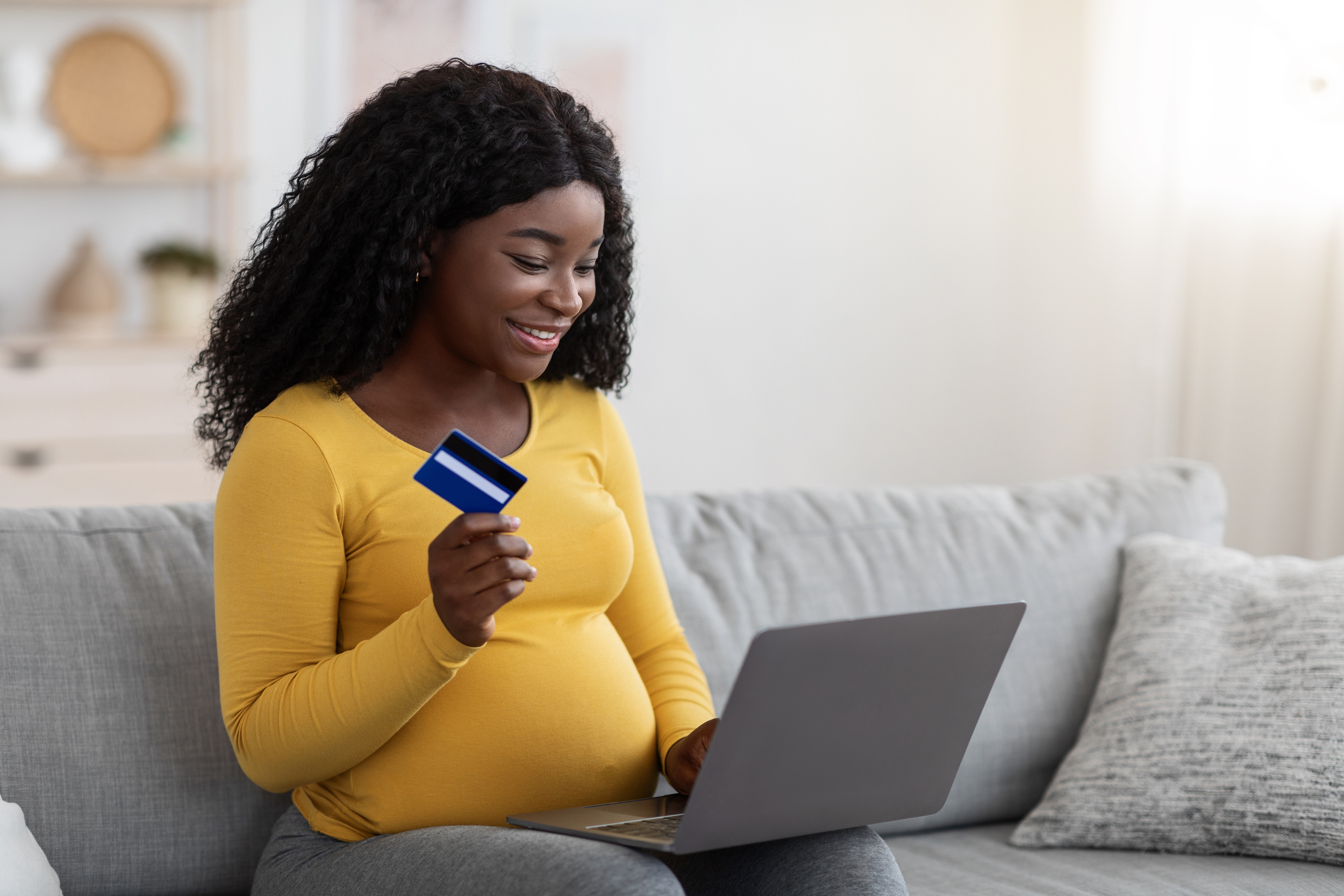 African single mother shopping online with laptop and credit card