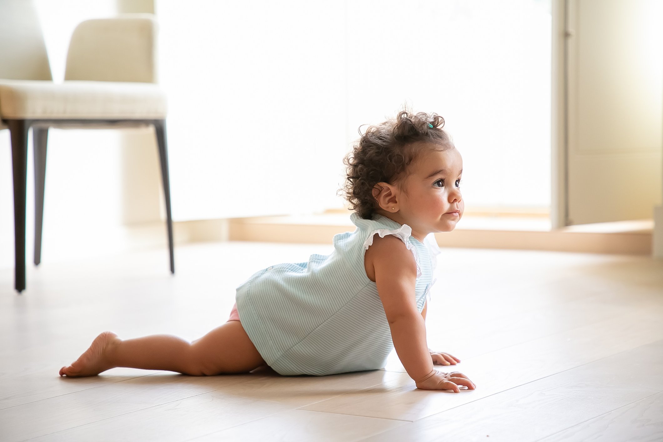 Adorable dark curly haired baby girl wearing pale blue cloth