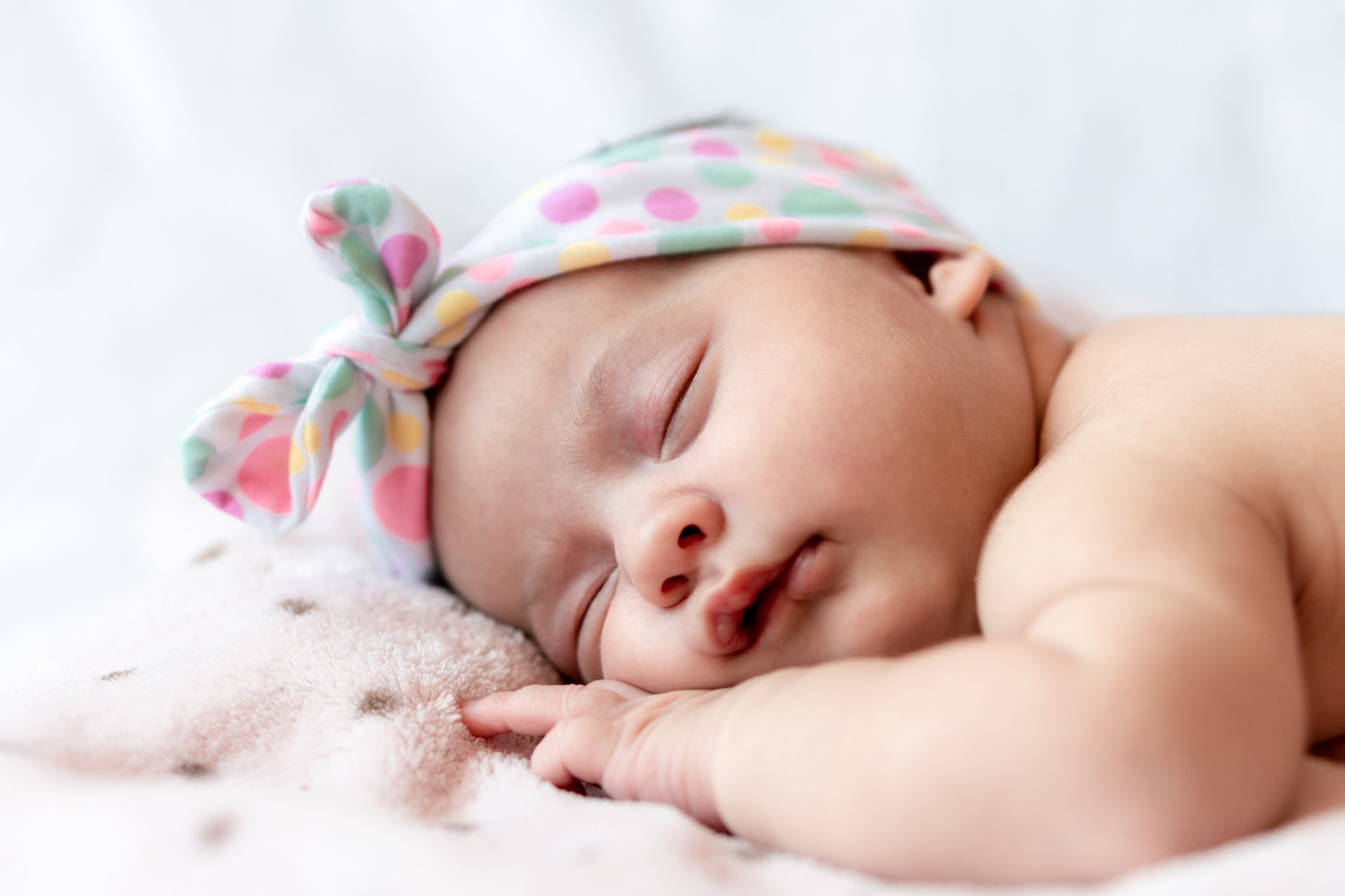 Childhood, care, motherhood, health, medicine, pediatrics concepts - Close up Little peace calm naked infant newborn baby girl in pink hat sleeps resting take deep nap laying on tummy on soft bed