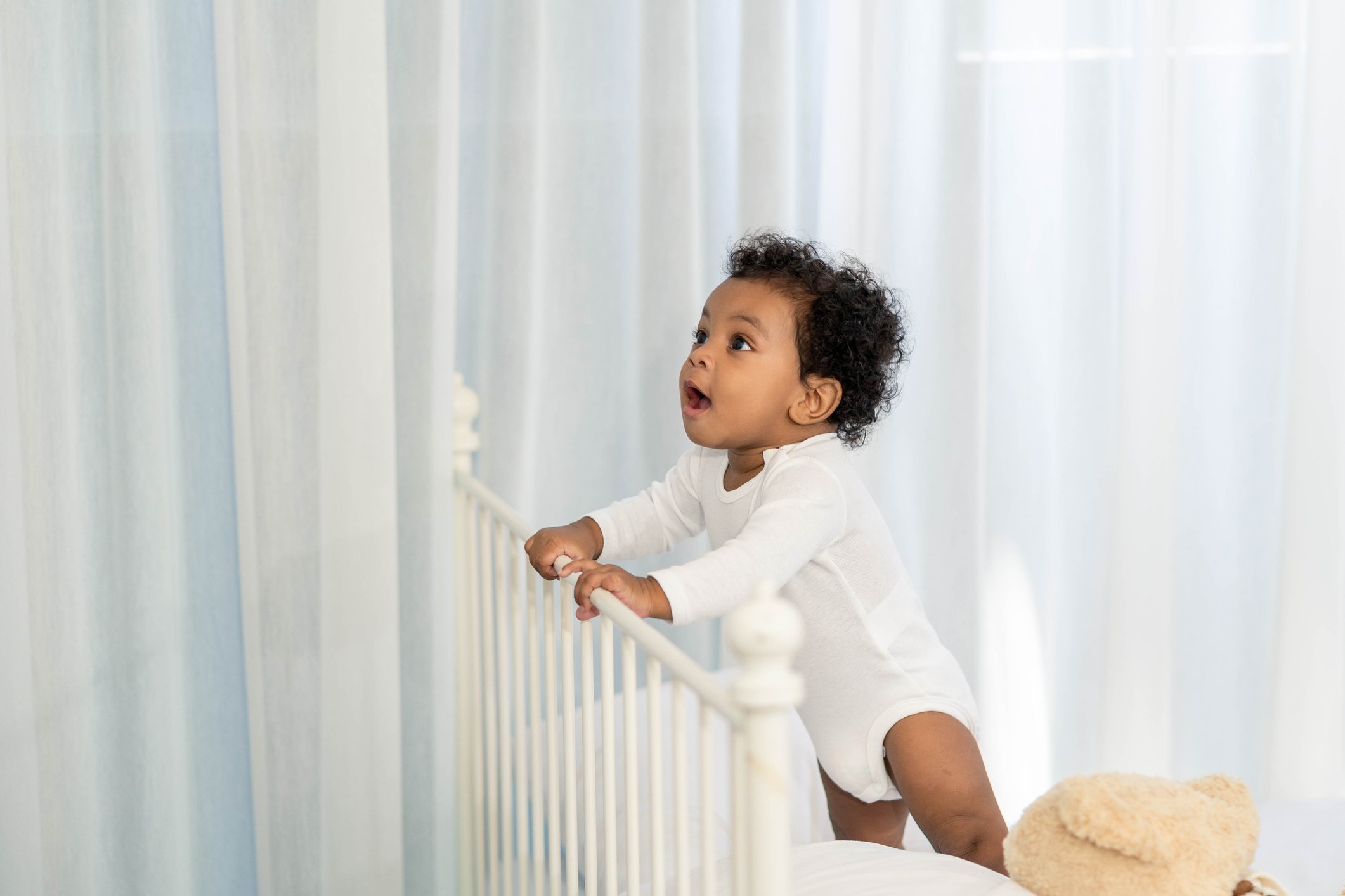 Happy African American Little baby boy climb the head of the bed and looking for some thing to learn