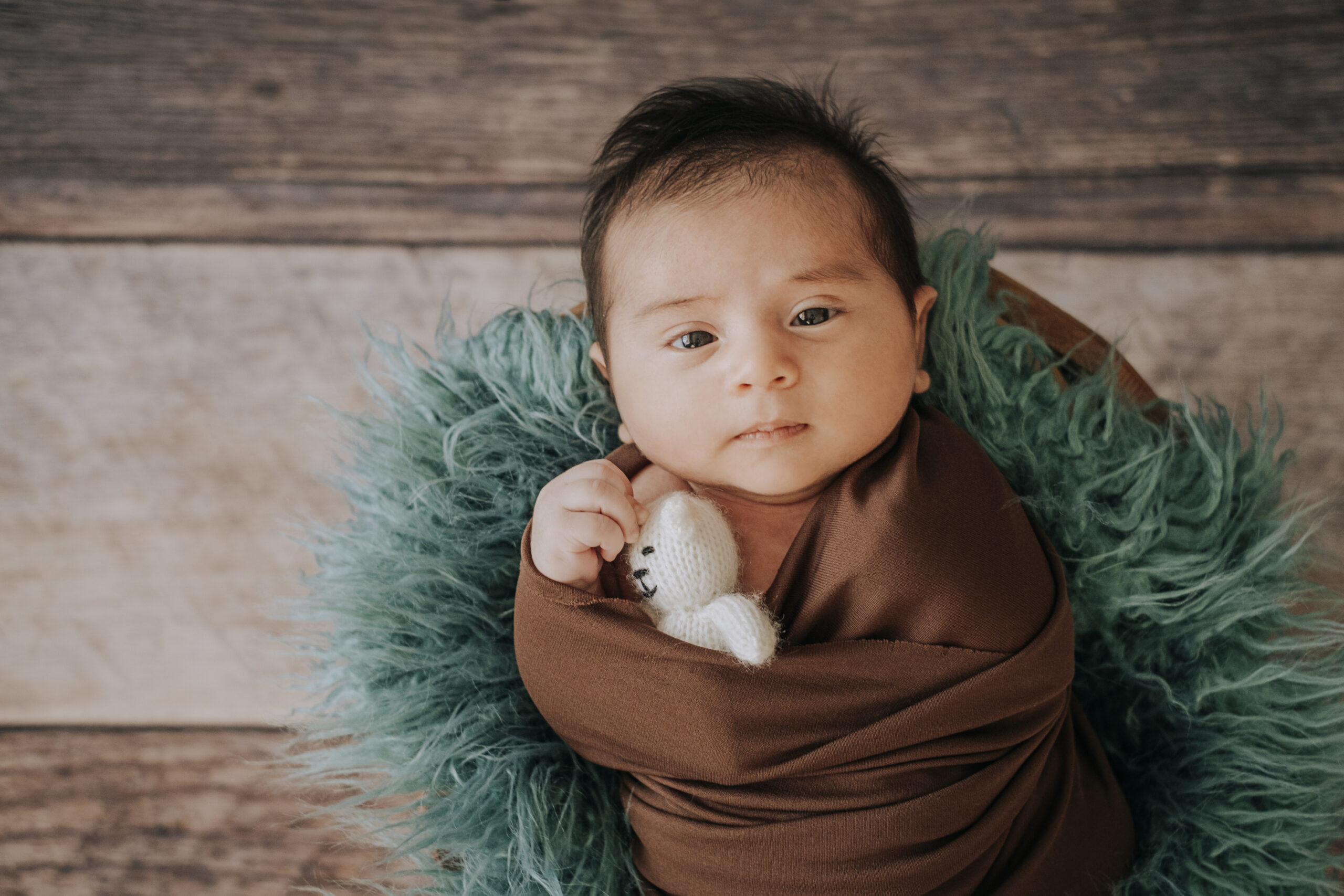 Little baby boy with knitted hat in a basket, happily smiling and looking at camera, isolated studio shot
