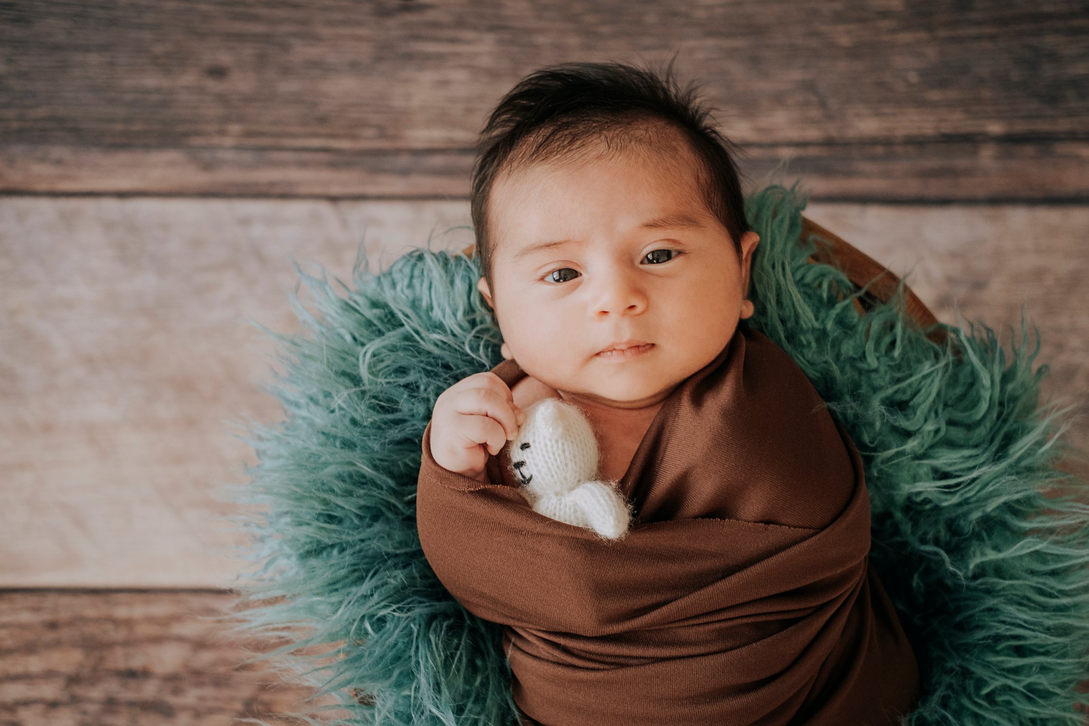 Little baby boy with knitted hat in a basket, happily smiling and looking at camera, isolated studio shot