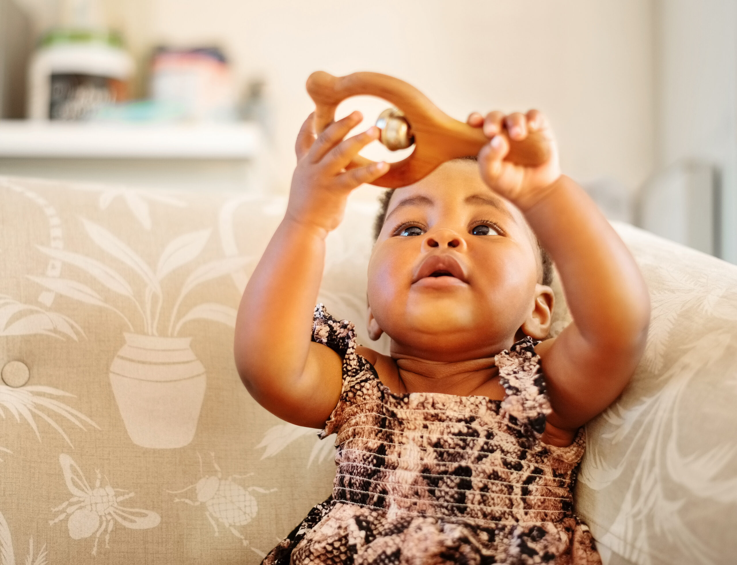 Baby girl playing with rattler toy at home
