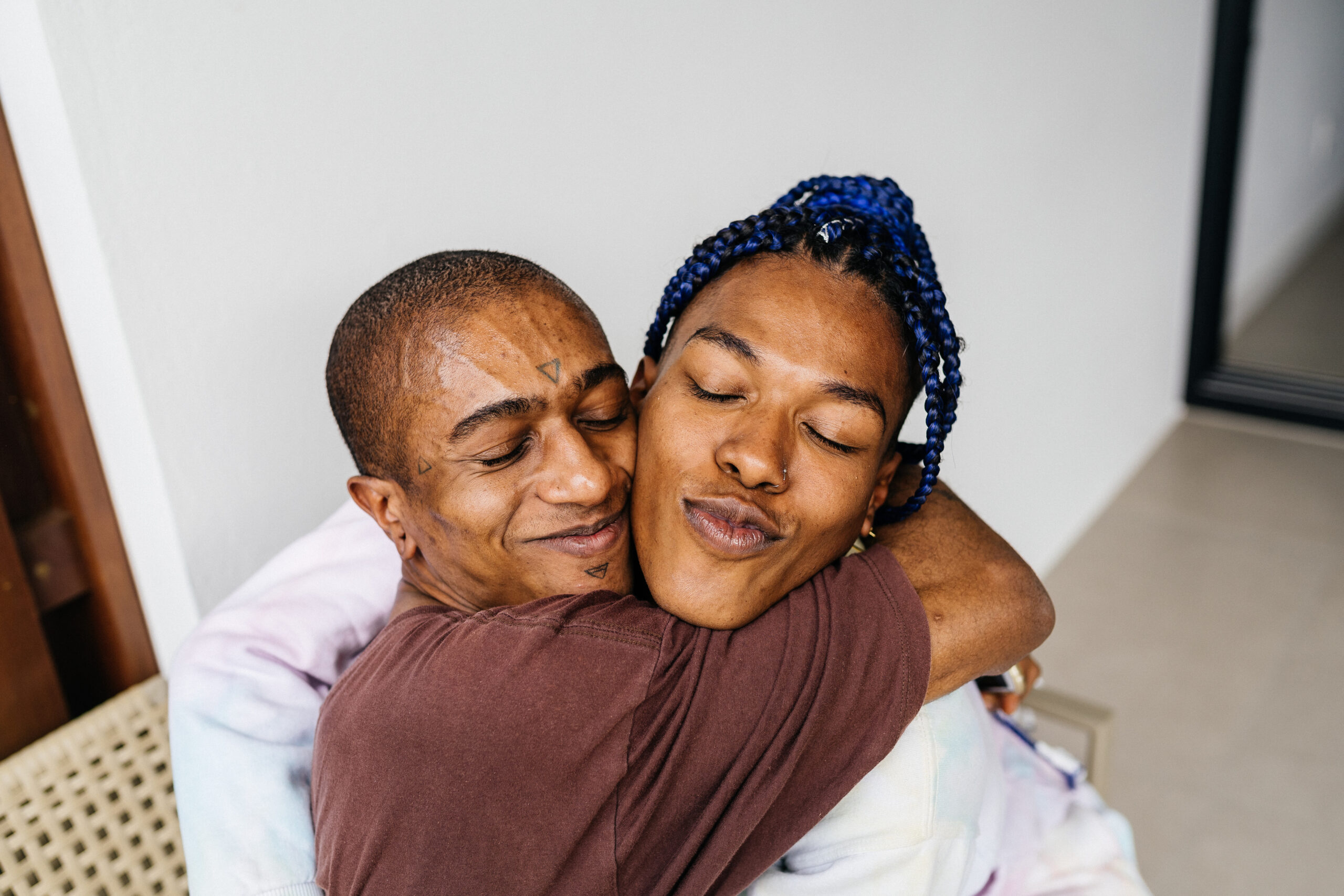 Trans woman and non-binary person hug each other affectionately