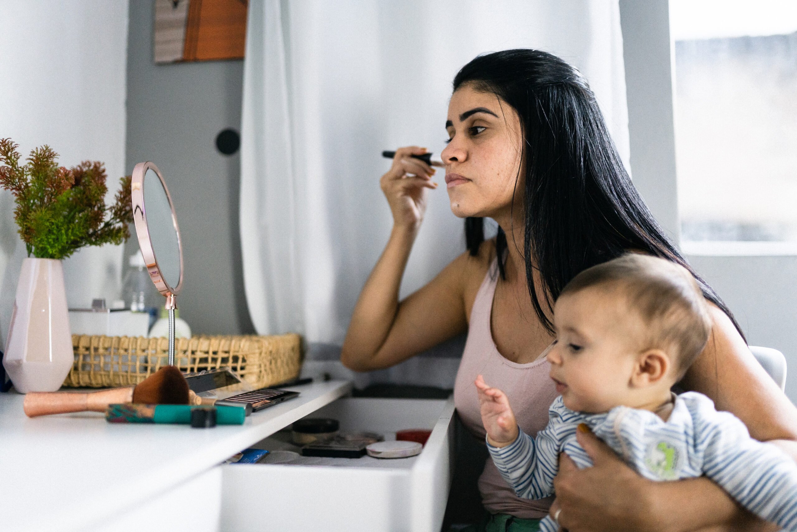 mom putting on makeup with baby