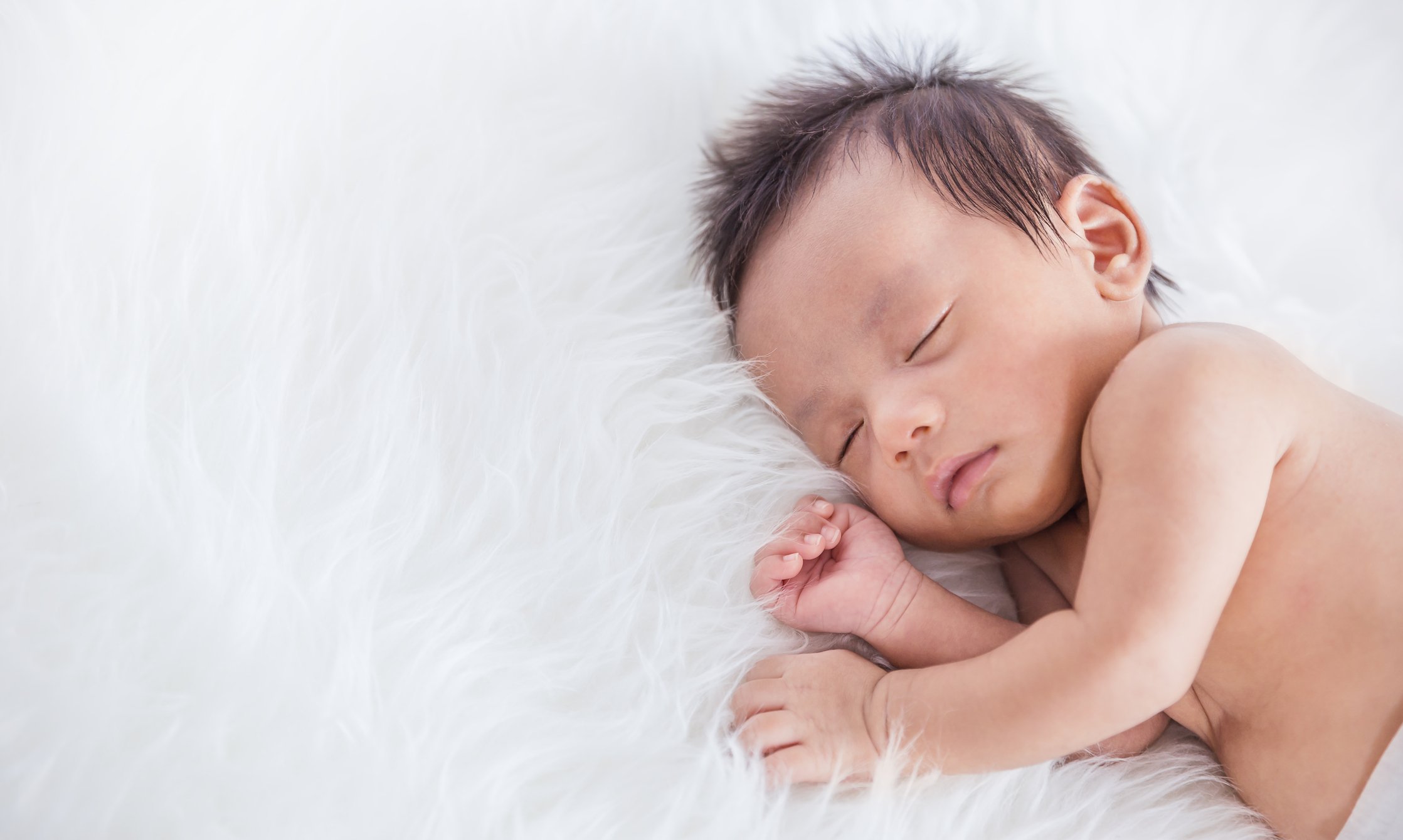 Closeup portrait of sleeping asian happy newborn baby over white background on hospital bed, Family love newborn nursery day care healthcare medical concept.