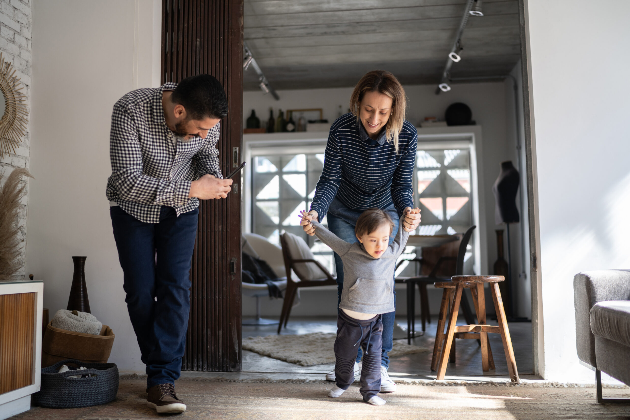 Father filming baby son's first steps - boy with special needs