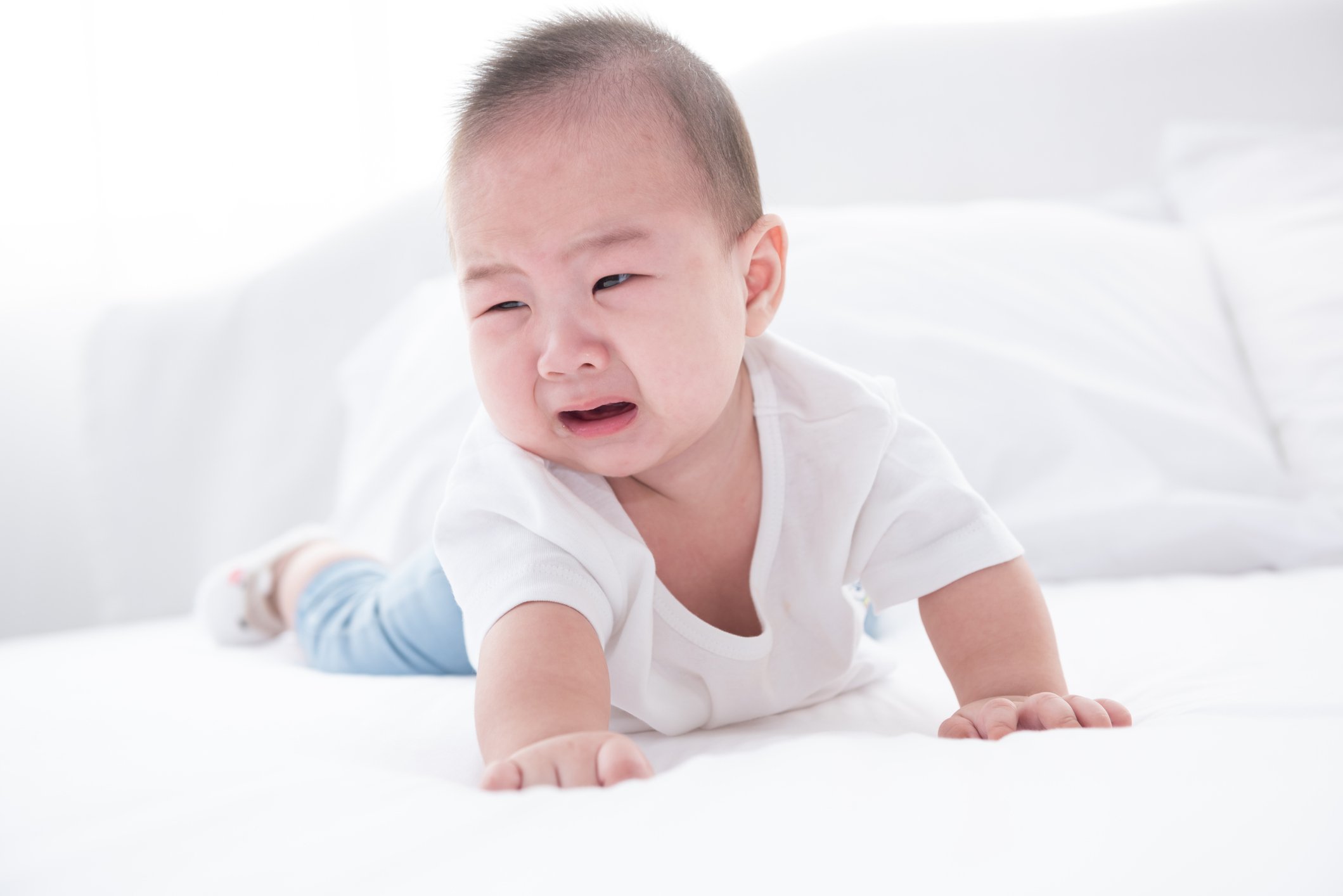Asian infant crying baby. child tired and hungry on white bed