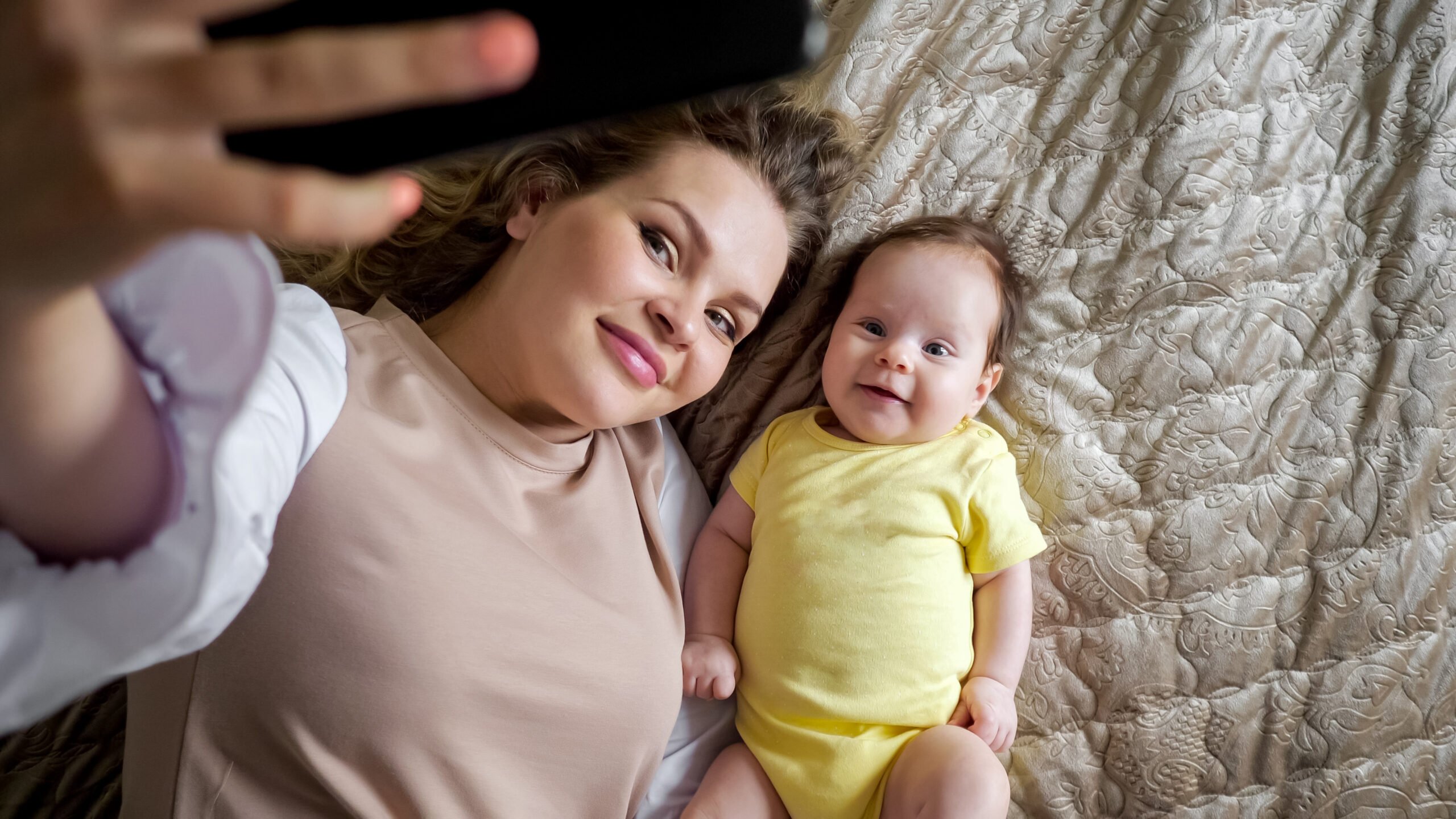 Jolly young mother with curly hair takes picture of daughter
