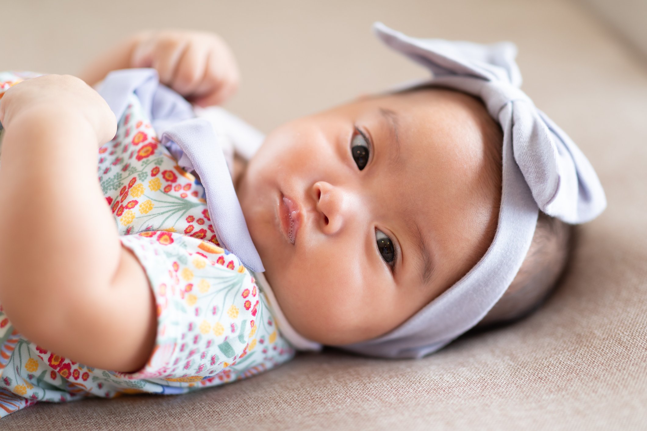 Adorable Asian baby girl lying on bed looking at camera.Cute little baby smiling and happiness relaxing in bed.Portrait of asian baby newborn in bedroom,Soft focus
