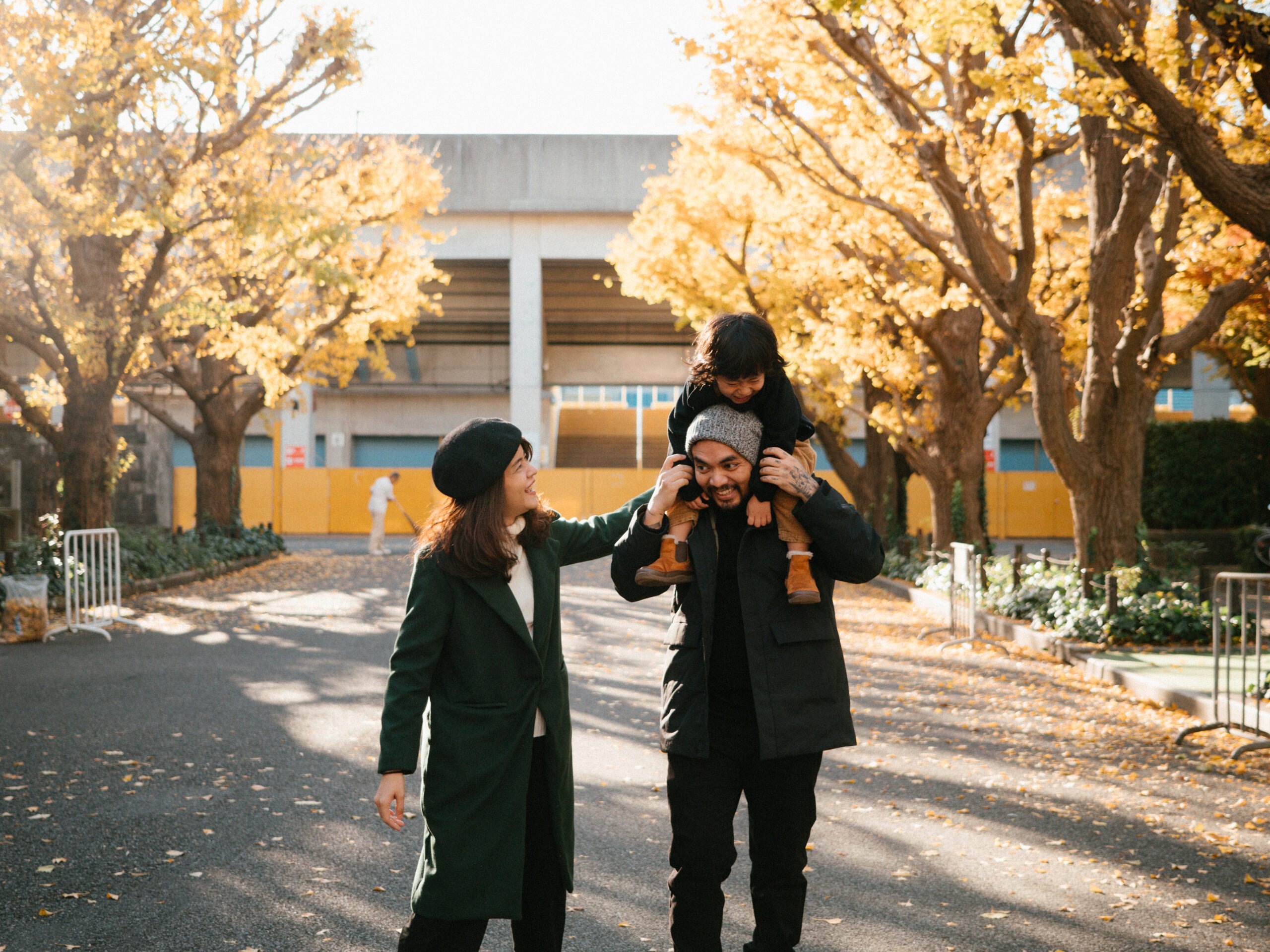 Father and mother holding his son in forest in sunset at ginkgo park.