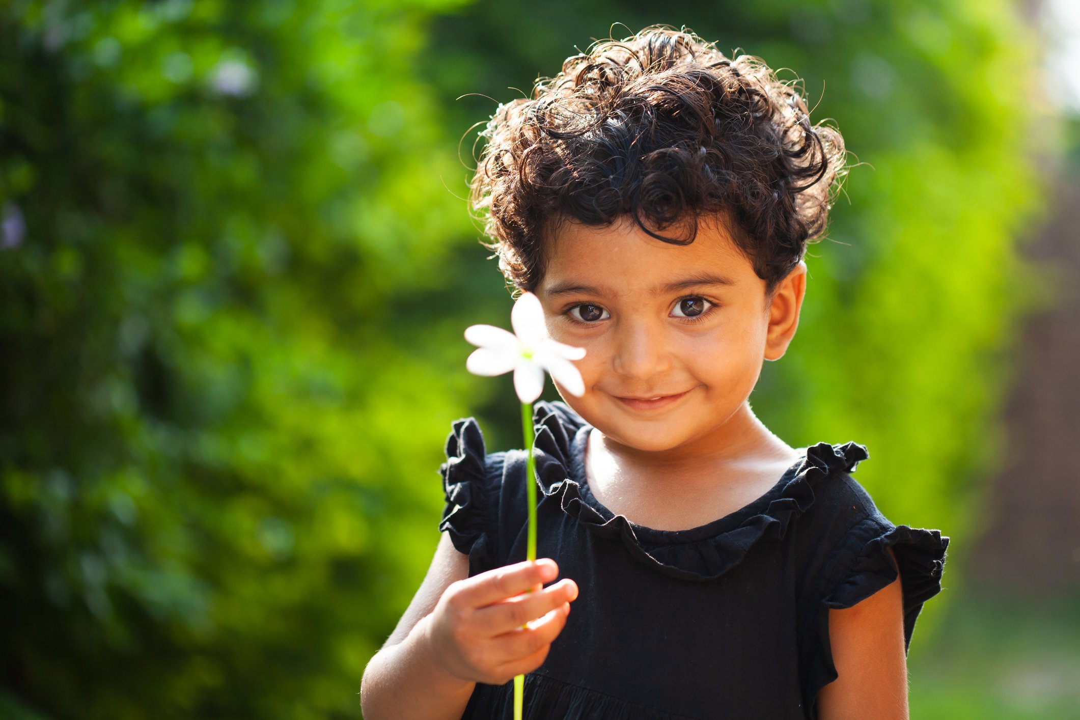 A small girl holding a flower in her hand