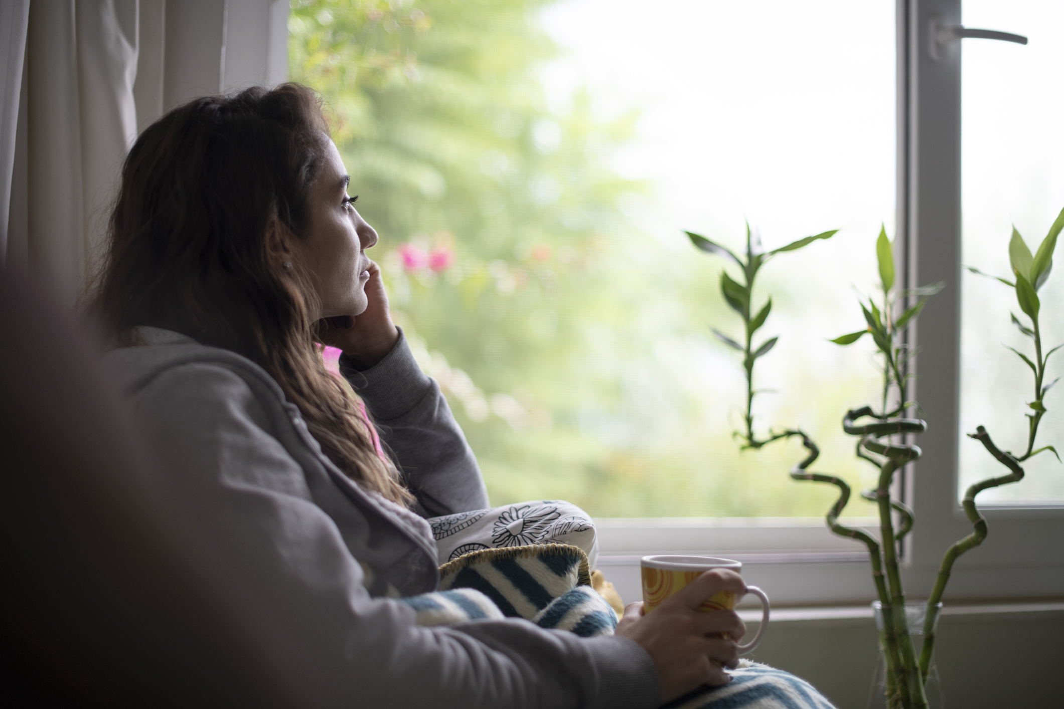 woman in pain drinking tea on a couch
