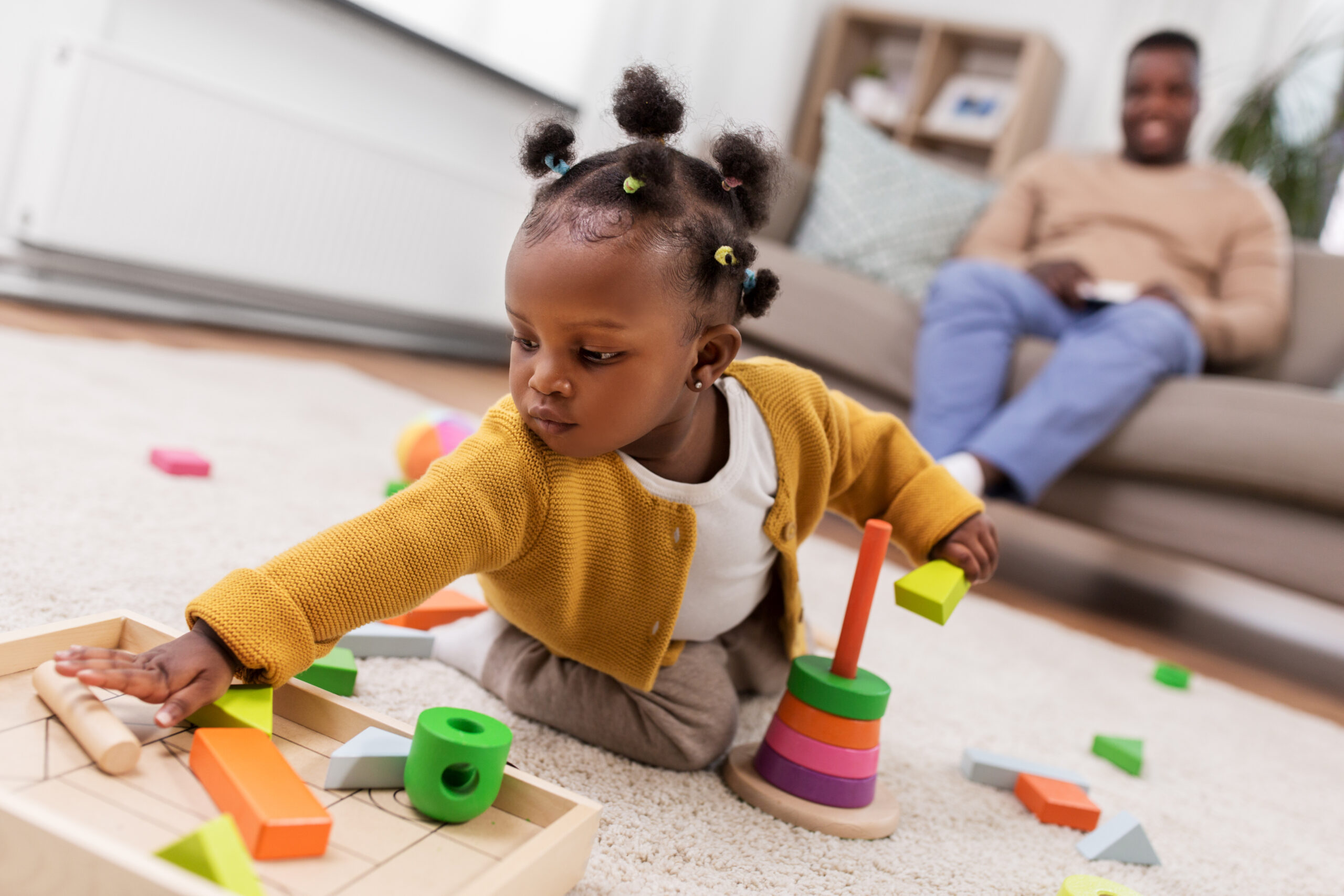 african baby girl playing with toy blocks at home