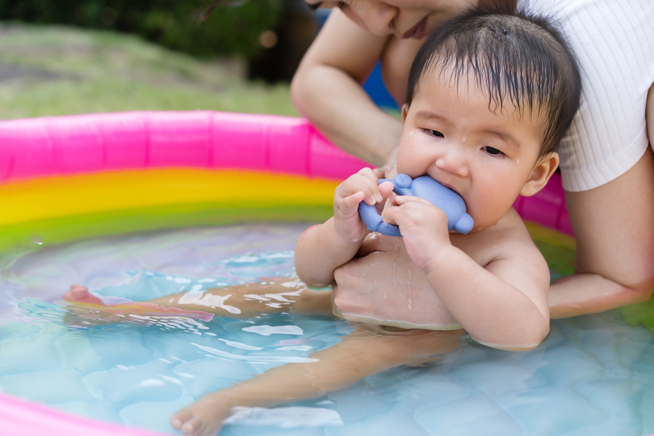 baby carried by mother enjoying in Inflatable pool