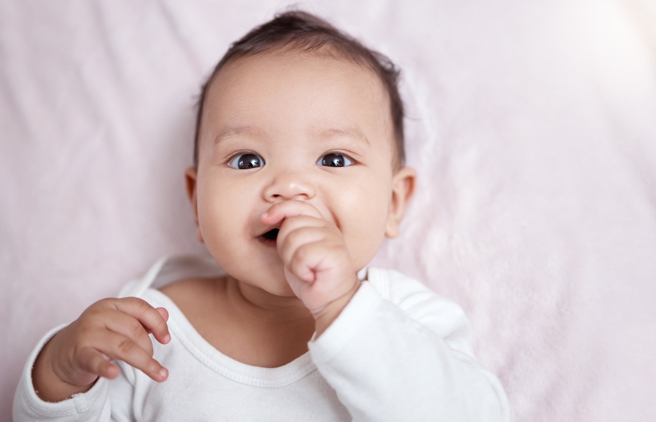 High angle shot of an adorable baby sucking his fingers at home