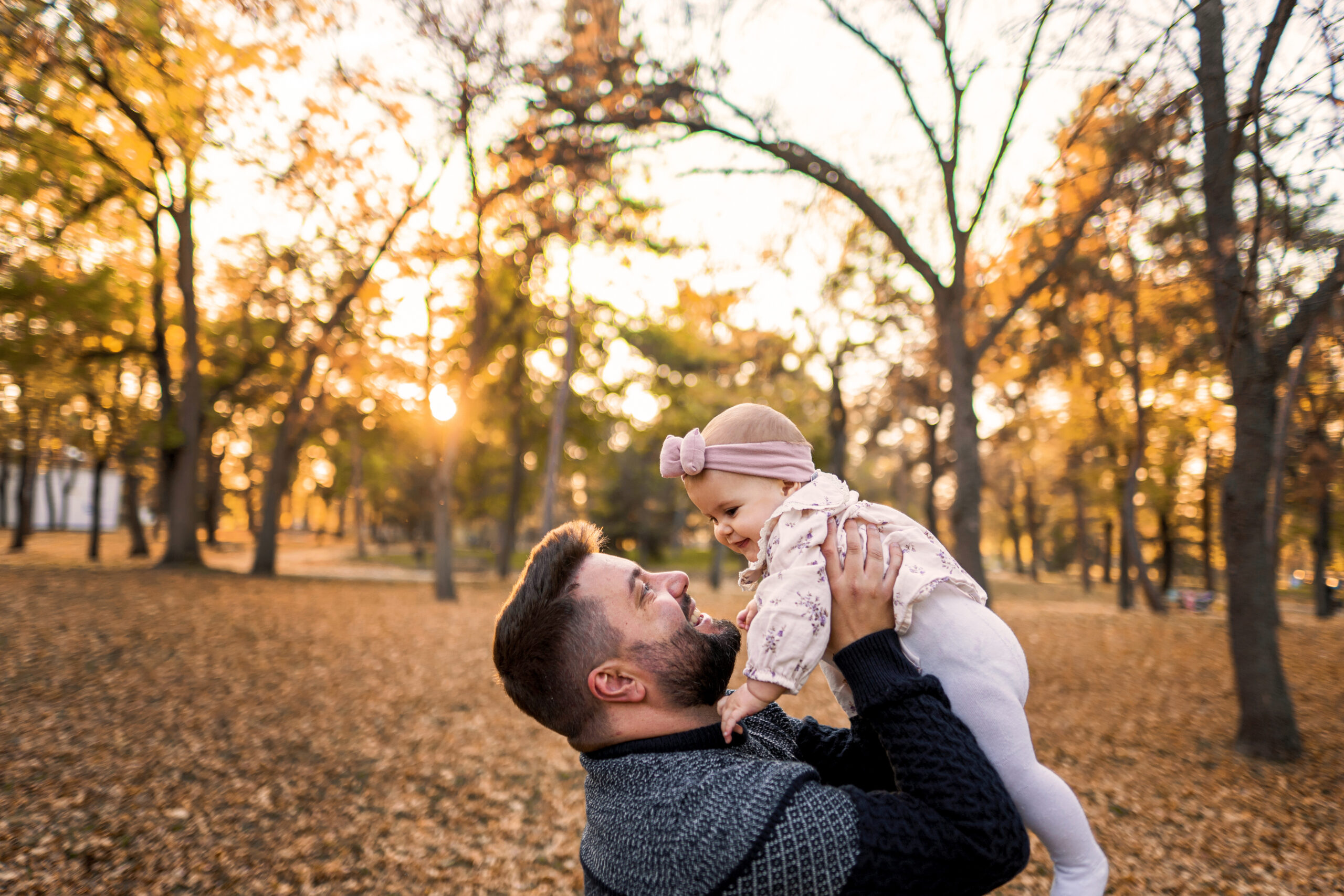 Father playing with his daughter outside on a cozy autumn day
