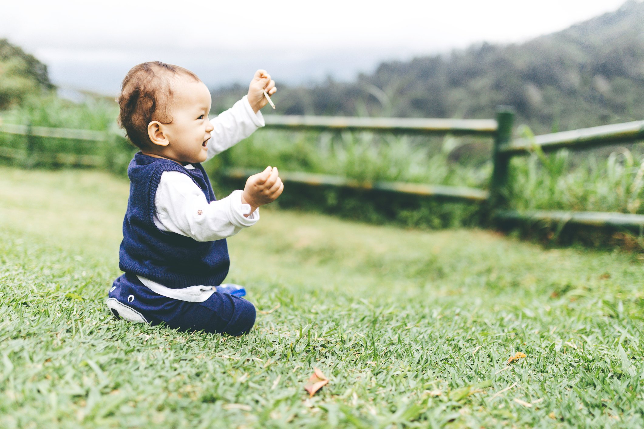 Baby boy playing and running on lawn in spring
