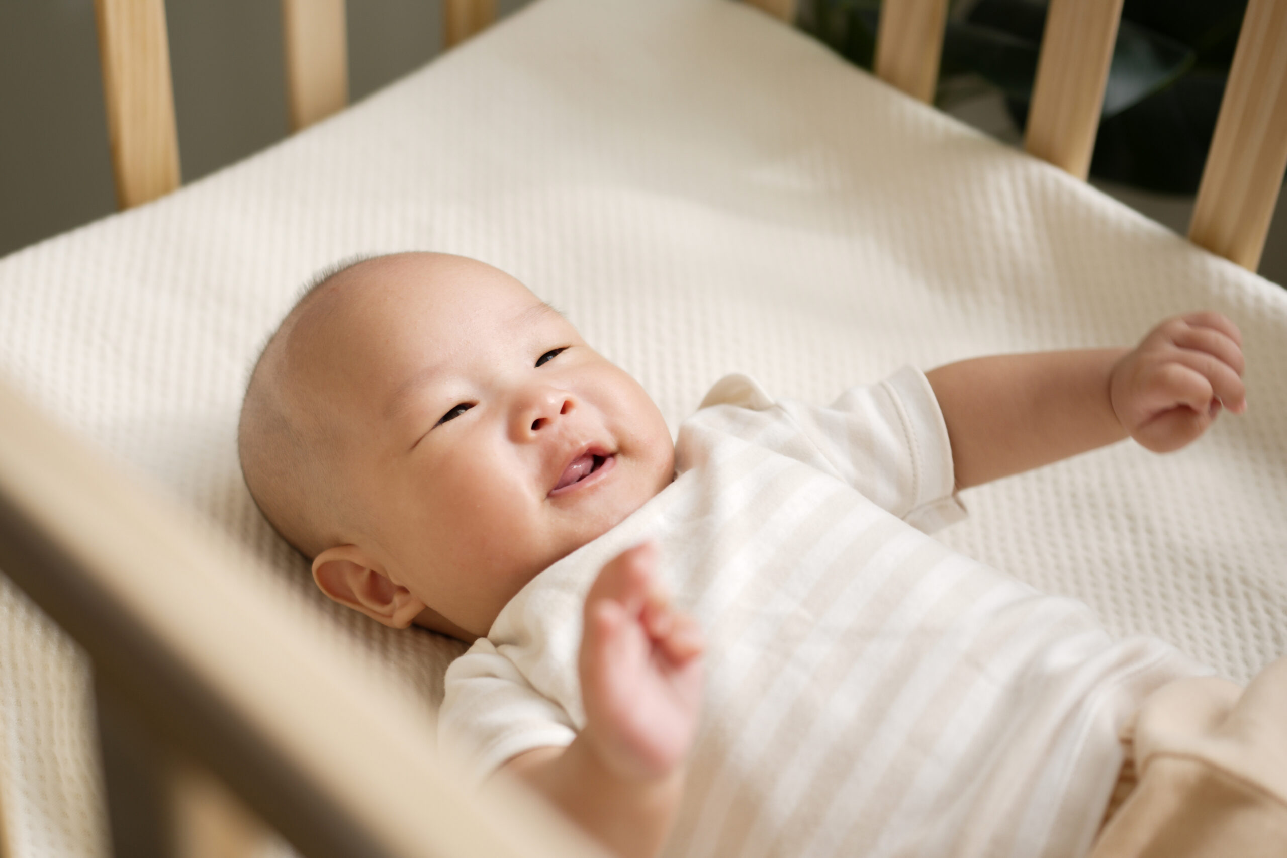 Happy Asian newborn baby smiling and laughing in crib