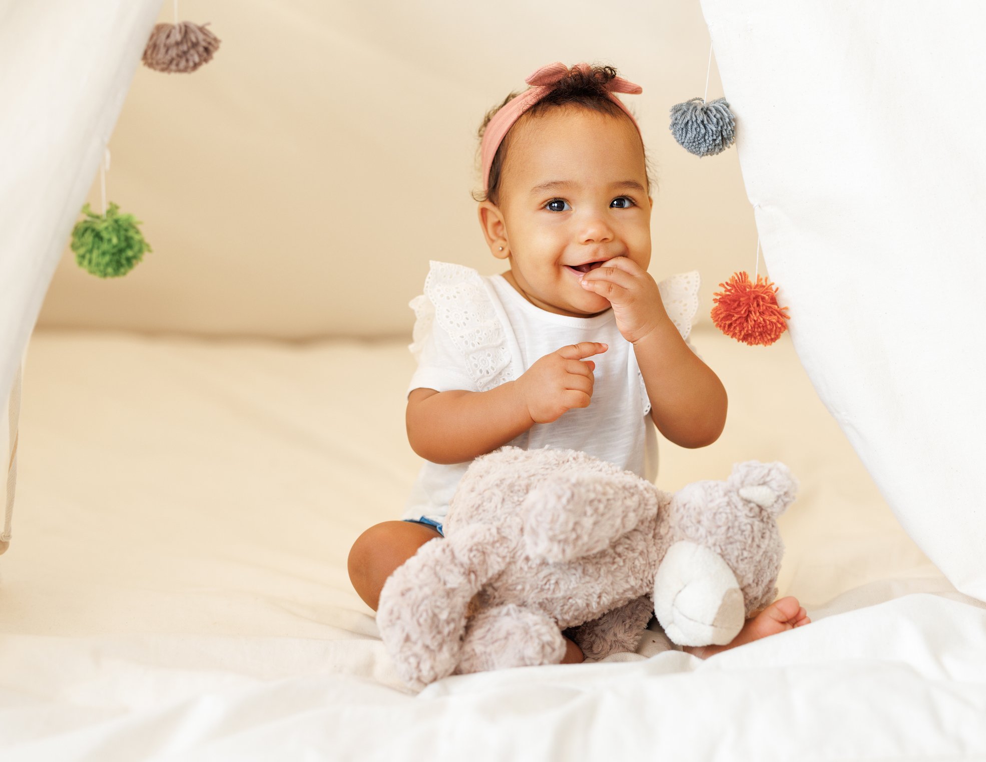 Cute adorable african american little baby girl infant wearing pink bow headband in teepee tent