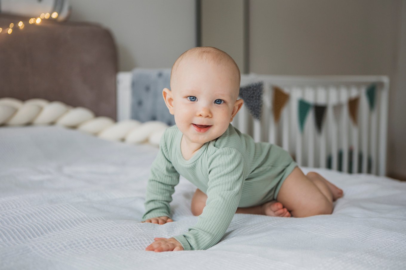 Adorable barefoot child smiling while sitting on bed