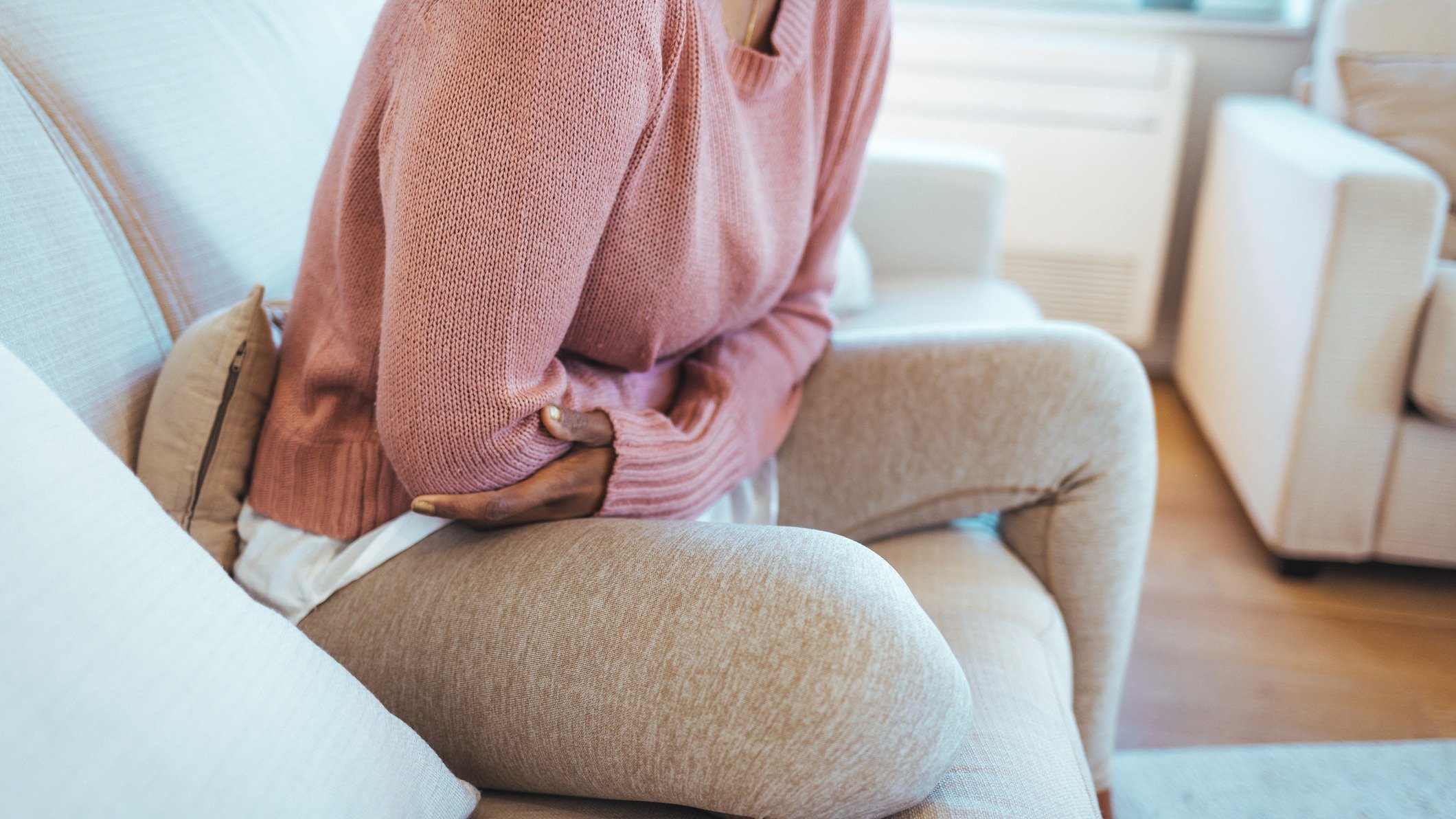 woman with arms over abdomen, postpartum pain, how long do you bleed after childbirth
