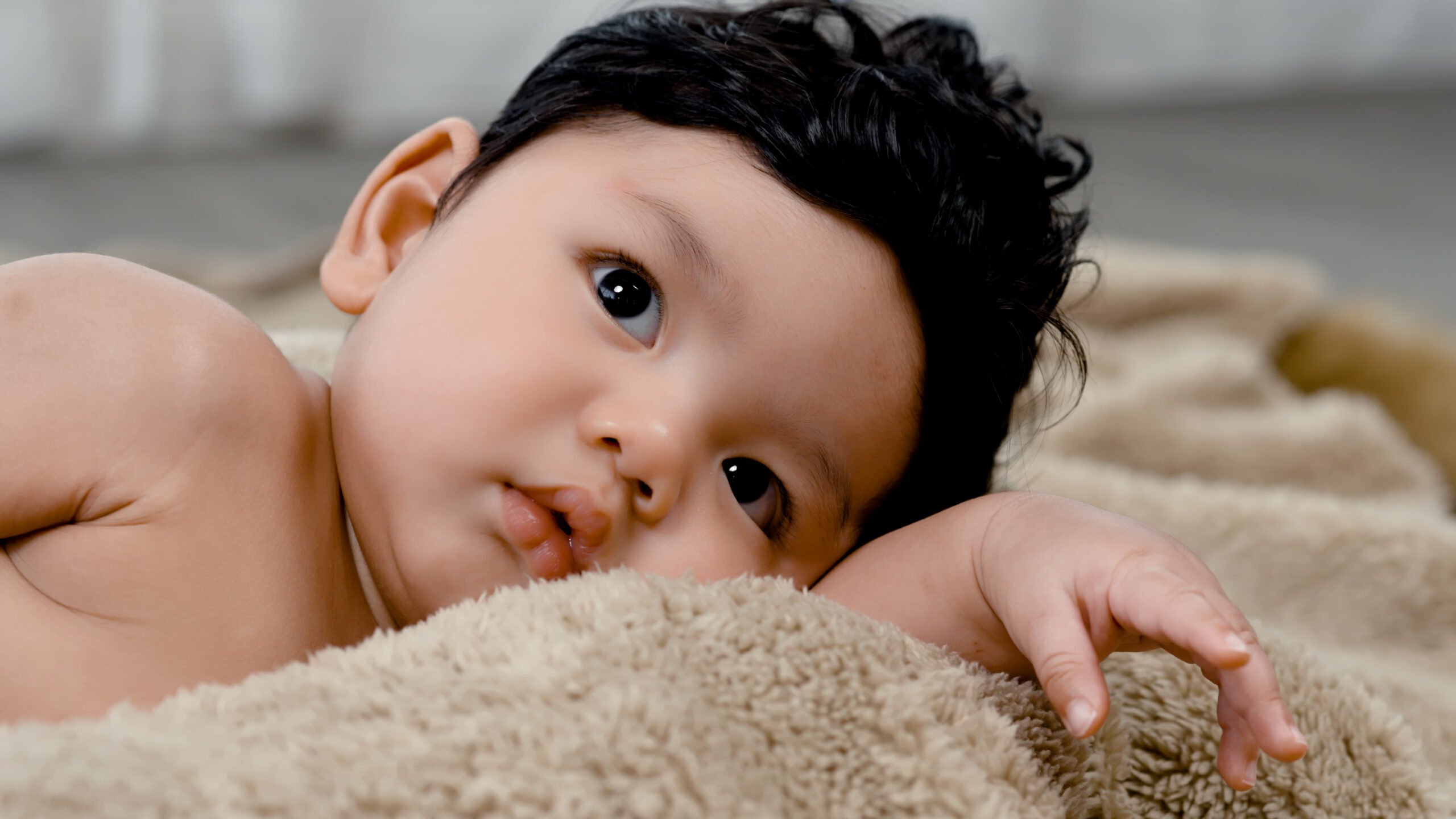 A 4-month-old Asian newborn, undressed, just woke up looking at her mother with bright eyes. Concept Happy Family.